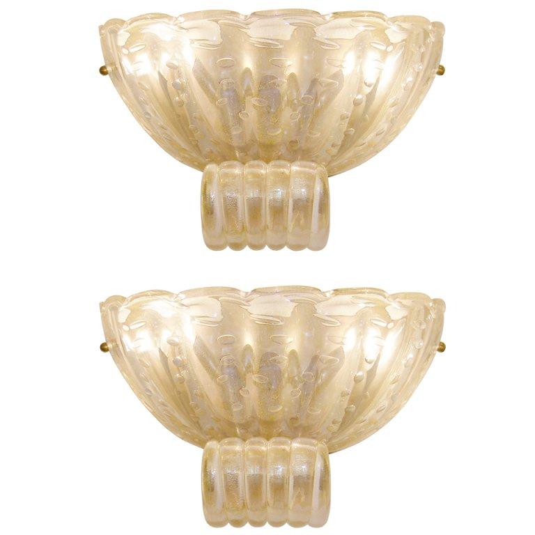 A pair of fluted pale amber glass sconces with controlled bubbles and gold particles throughout the glass with brass hardware and frame by Barovier.

Italian, Circa 1950's.




 