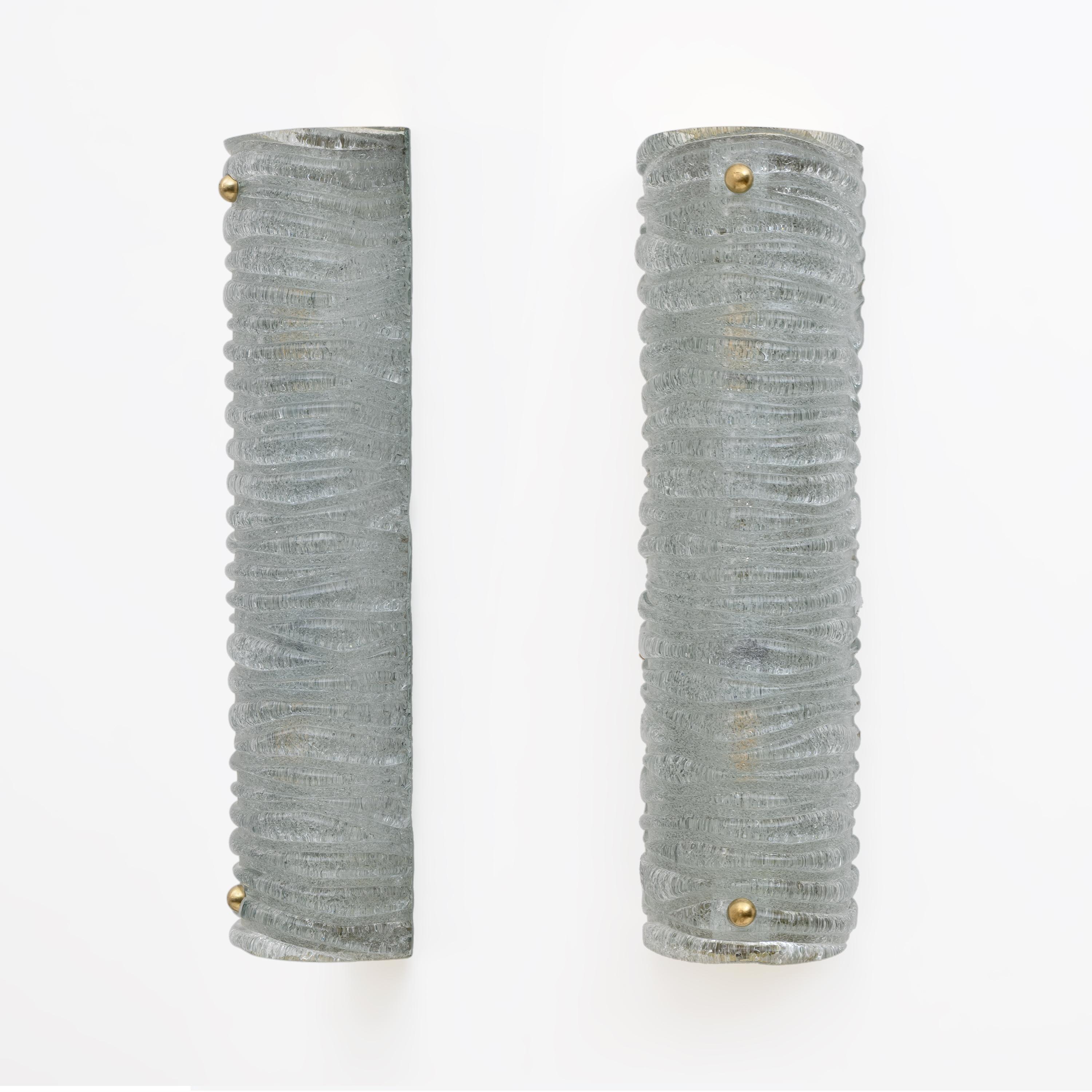 Pareja de apliques de cristal de Murano color aguamarina, cristal texturado con efecto corteza y acabados en latón. Las lámparas están equipadas con dos portalámparas, cada uno con un casquillo E14 para Europa o un casquillo E12 para Estados Unidos.