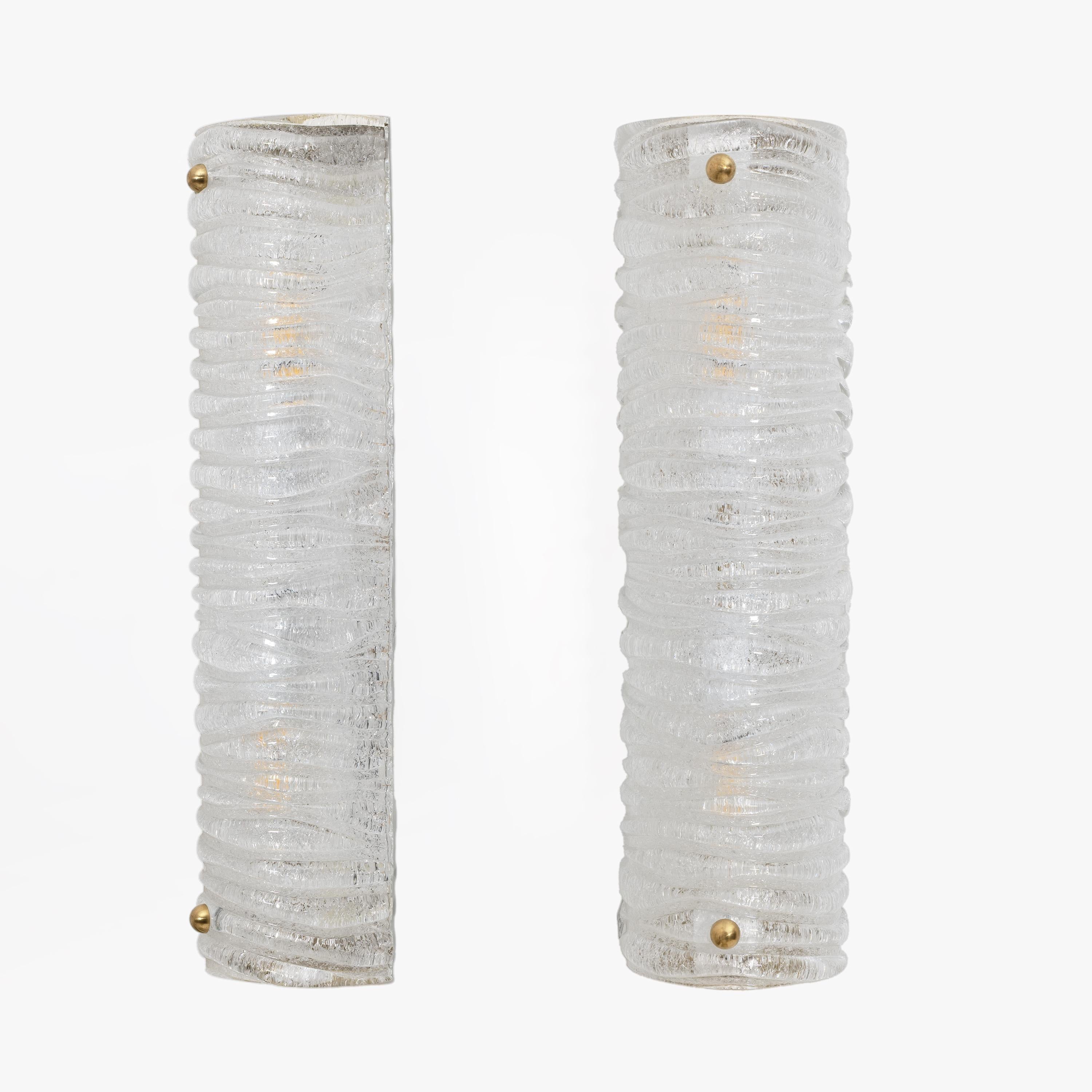 Pareja de apliques de cristal de Murano texturado con acabado efecto corteza y remates de latón. Las lámparas están equipadas con dos portalámparas, cada uno con un casquillo E14 para Europa o un casquillo E12 para Estados Unidos. Se trata de un
