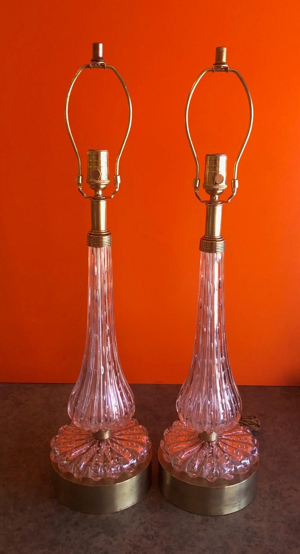 A gorgeous pair of pink, hand blown Barovier & Toso Murano art glass table lamps, circa 1950s. The lamps are brass single socket on ribbed baluster form pink bodies with controlled bubbles (bullicante) and brass banding on a well patinated brass