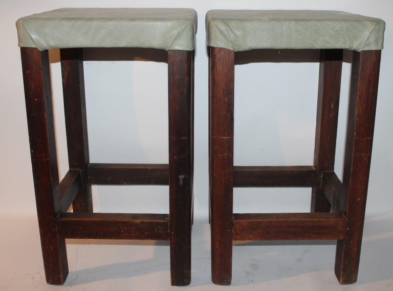 Pair of barstools with sage green leather seats.