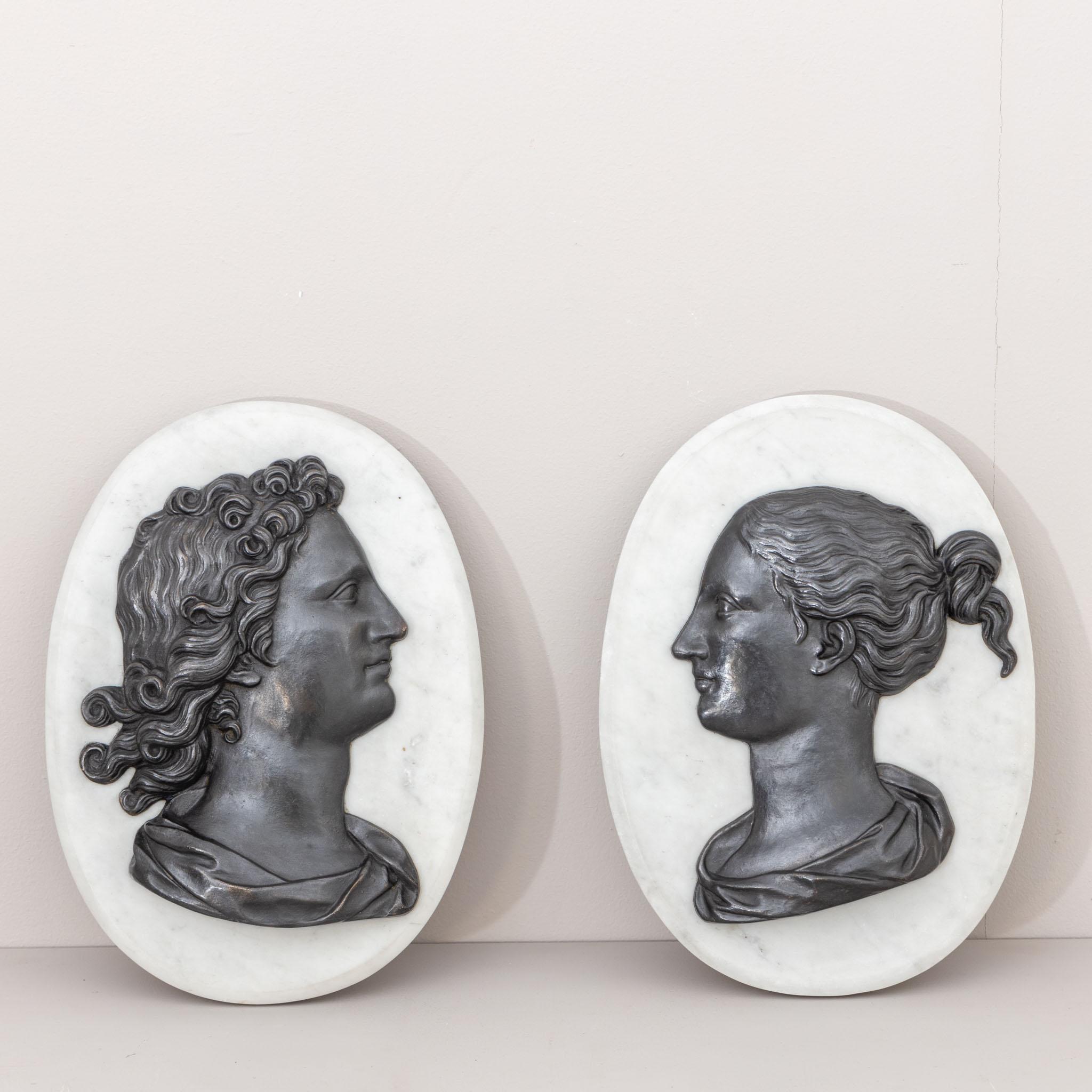 Pair of bas-reliefs with antique profile portraits in bronze mounted on an oval marble disc.