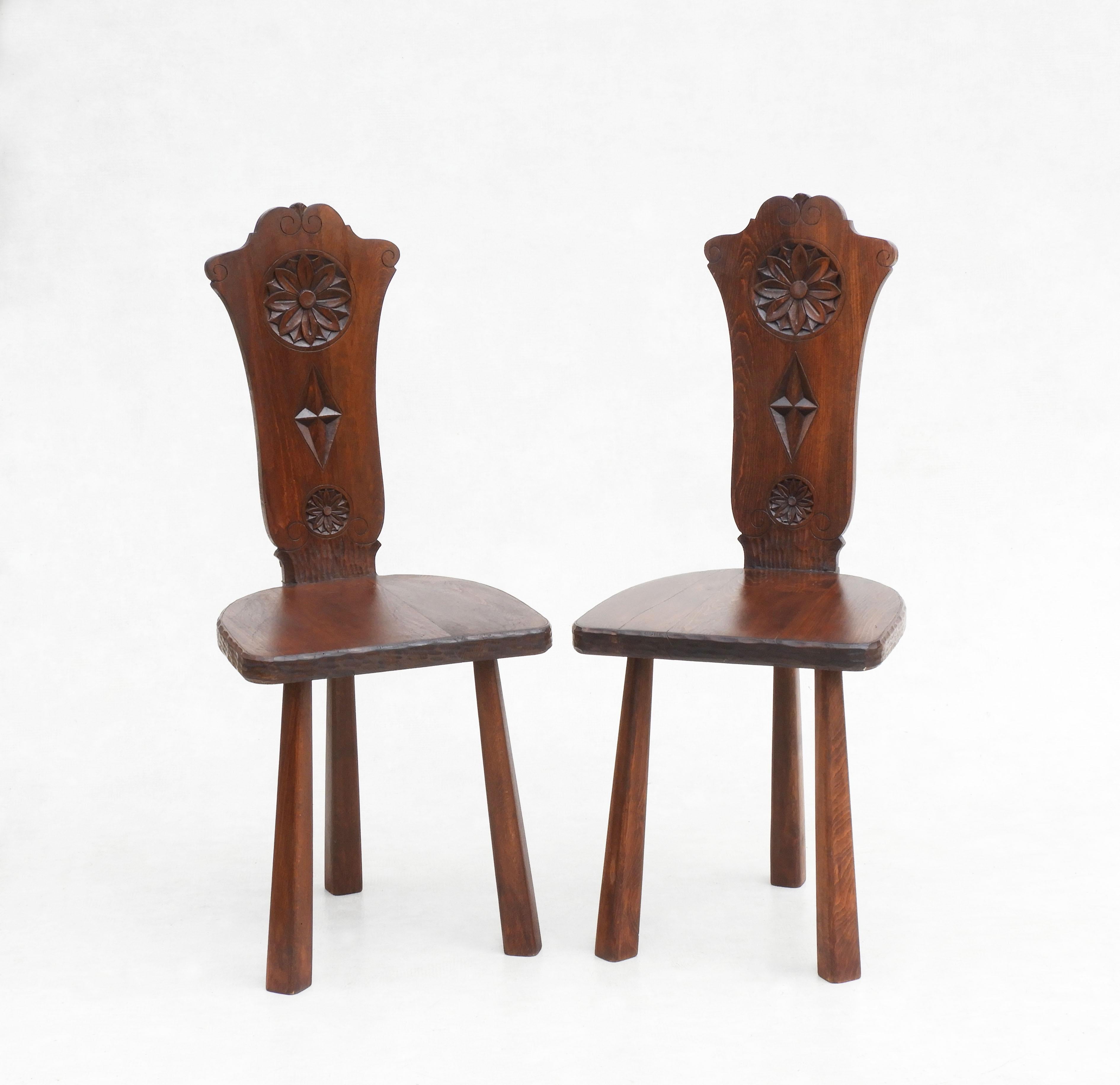 A fabulous pair of oak three-legged chairs, crafted in the Basque region of France/Spain C1950.  Beautifully decorated with carved flowers and diamond detailing, these chairs are a really nice example of mid-century West European Folk Art, in great