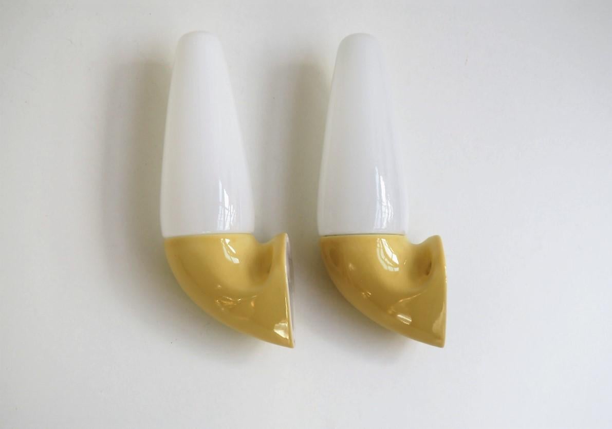Pair of vintage bathroom lights in timeless design manufactured by Swedish Ifö during the 1960s and designed by Sigvard Benadotte.

This model - Ifö number 6035 - came in more colors and here the porcelain base is light yellow together with shade