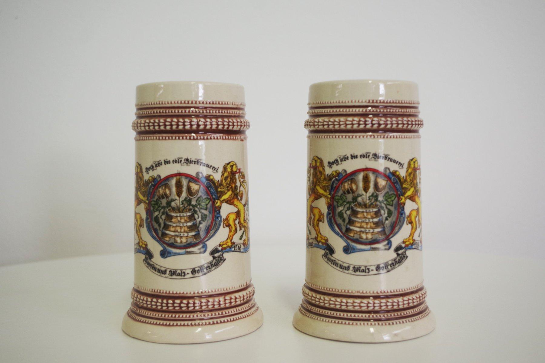 Pareja de jarras de cerveza de porcelana bávara - Años 80

Este exquisito par de jarras de cerveza de porcelana bávara de la década de 1980 combina la artesanía tradicional con una elegancia atemporal. Con diseños bávaros clásicos, estas tazas son