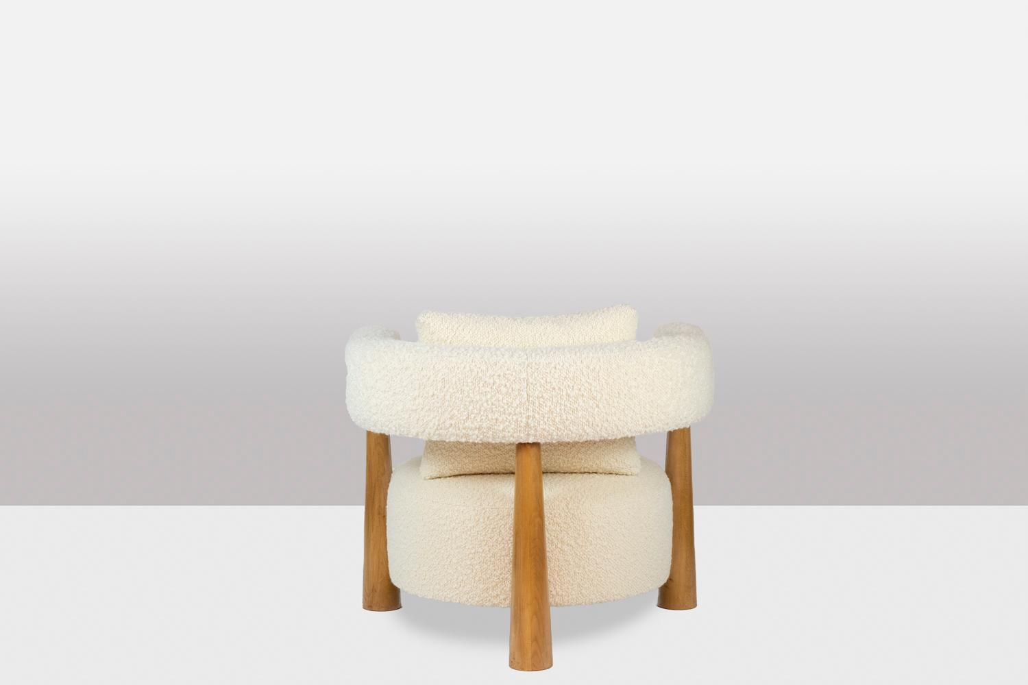 Pair of “bean” shaped or curved armchairs, in slightly veined solid blond beech with a gap between the base of the seat and the backrest, with its removable cushion. “Tripod” base, conical in shape, the 3 bases fitting into the backrest. Fabric with