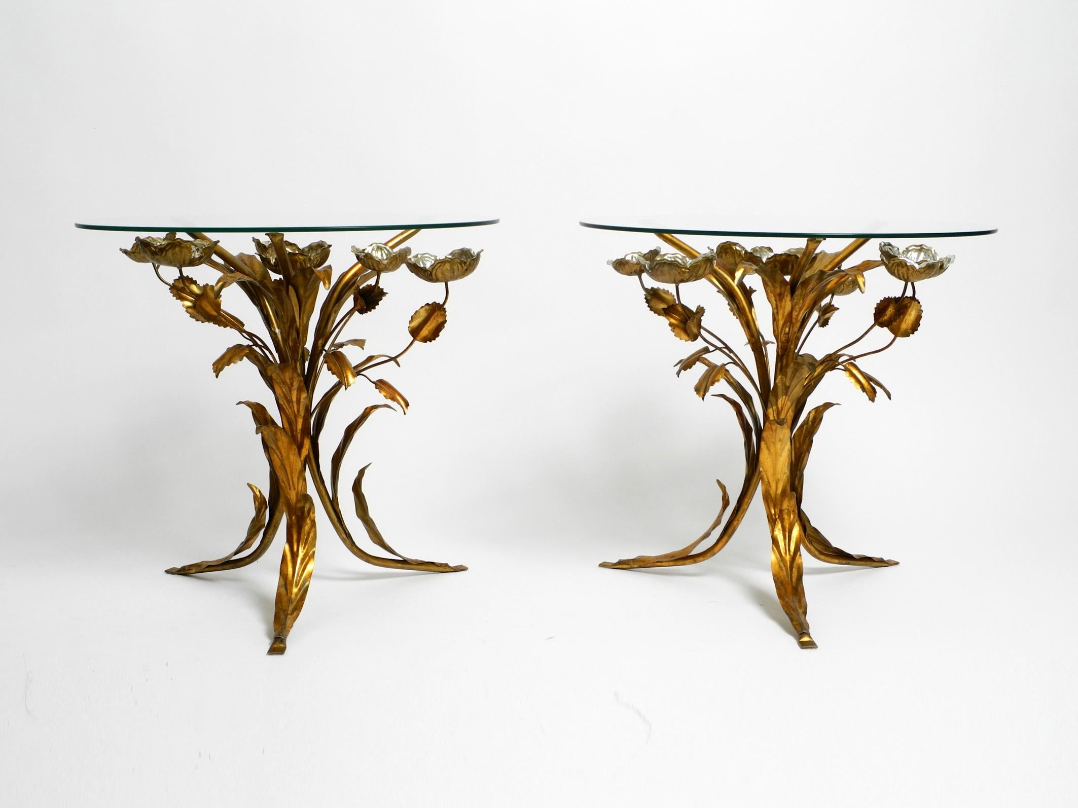 Pair of 1960s rare Florentine side tables or bedside tables.
The frame has three curved legs in the shape of plant leaves with a thick round glass top.
In the middle and outside there are different sized flowers in silver.
Great design with lots of