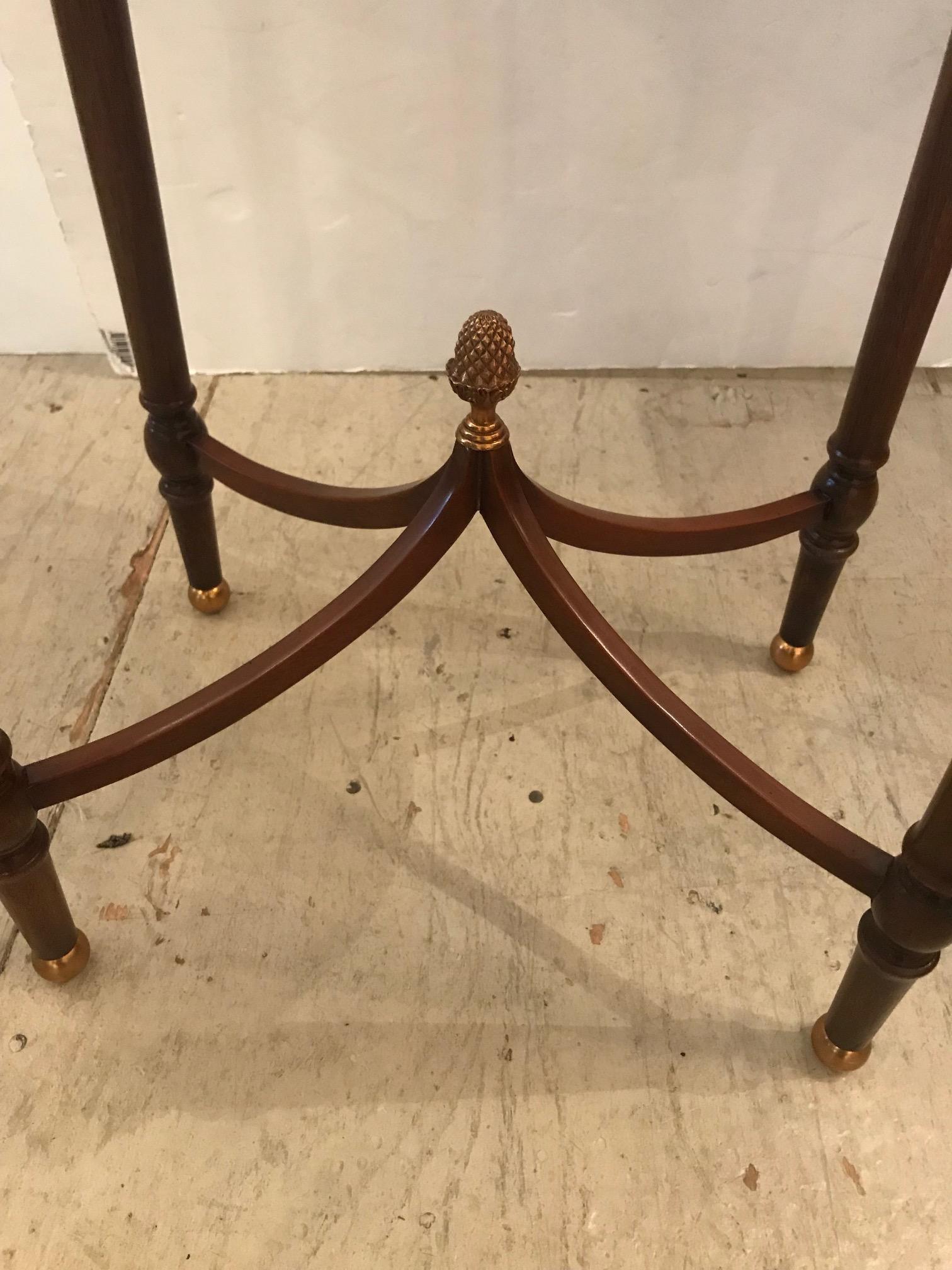 Pair of beautifully made Maitland-Smith oval side or end tables having tooled leather tops, lovely tapered legs with brass ball feet, and a gorgeous 4-piece stretcher underneath that meets in the center with an acorn finial.
 