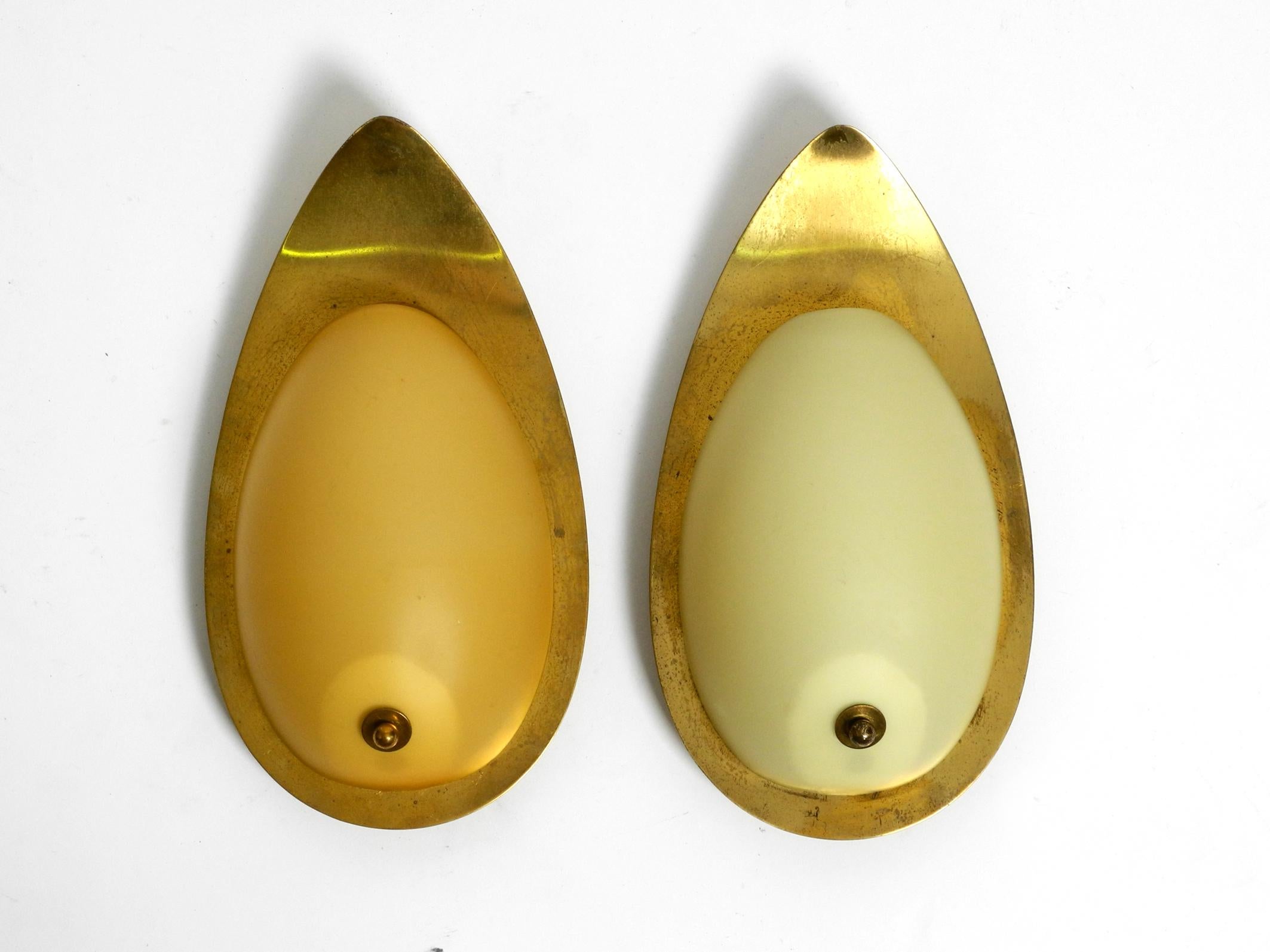 Pair of beautiful elegant mid-century brass sconces with beige glass shades .
Great elegant elaborate 1950s design. Made in Germany.
The frame is made of brass, the suspension on the back is made of another metal.
The shades are made of beige matt
