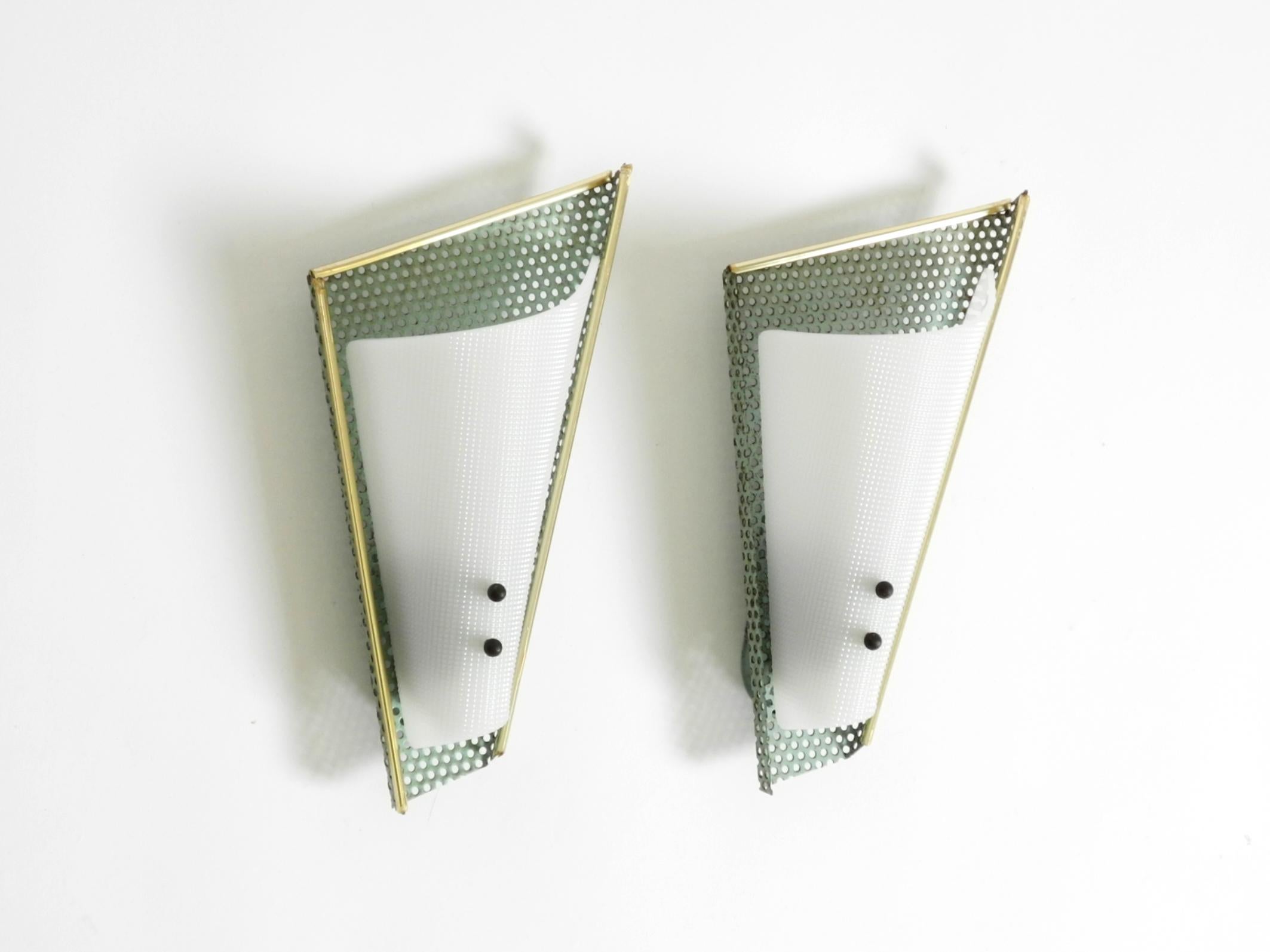 Zwei sehr schöne Mid-Century Modern Wandlampen aus perforiertem Metall mit weißen Plexiglasschirmen.
Ein typisches, schönes Design aus den 1950er Jahren, noch in der ursprünglichen mintgrünen Farbe.
Beide Plexiglasschirme sind in einwandfreiem