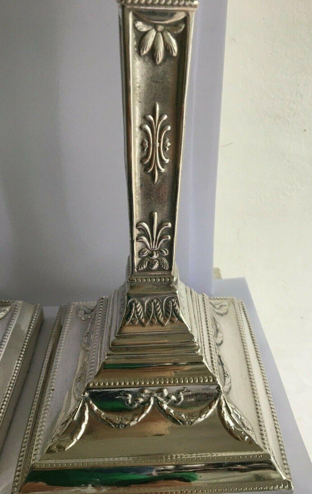 Paire de magnifiques chandeliers en métal argenté polonais

Fortement orné d'un design néoclassique.
Décoré de rinceaux de feuilles et de rubans. 
Les chandeliers sont en forme d'urne, agrémentés de guirlandes de rubans et de feuilles.
Elles sont