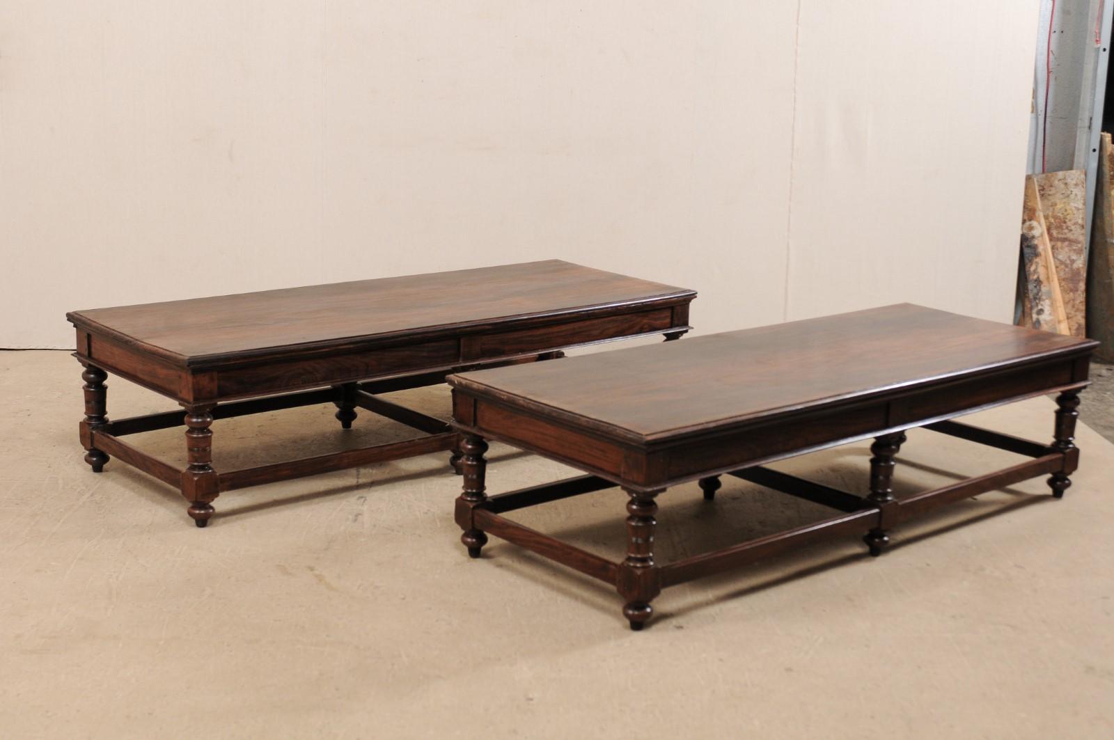 This is a pair of beautiful rosewood coffee tables or benches, depending upon your needs, from Kerala in India. These rosewood coffee tables each feature a long, rectangular-shaped top, just over 6 feet in length, raised upon 6 nicely turned legs,