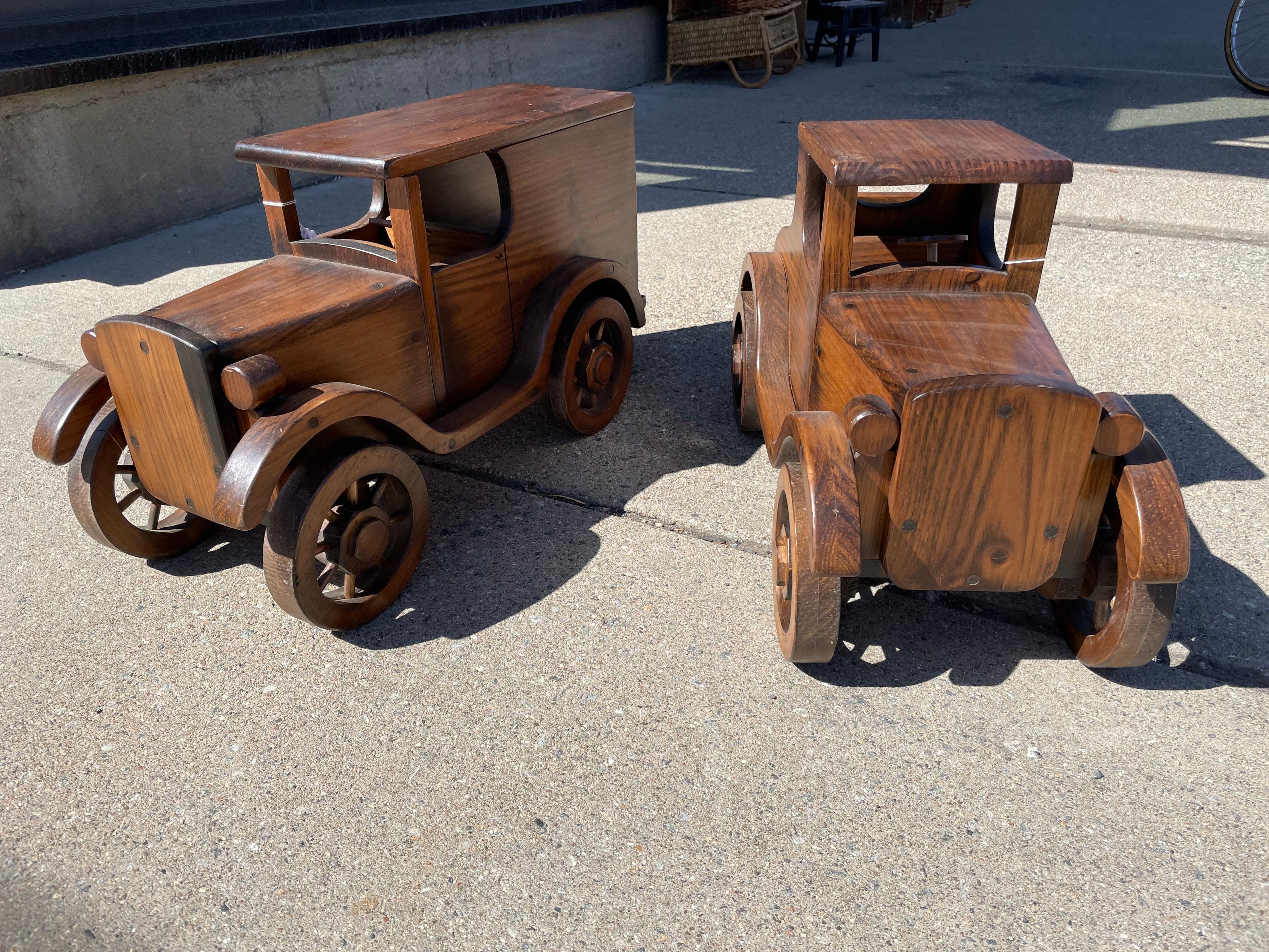 Large carved and pegged wood 1920s pair of automobiles, vintage 1970s, crafted by hand , having functioning wheels and steering wheel, Can be used to decorate kids bedroom or used as a cocktail table to add a whimsical flair to any space. The