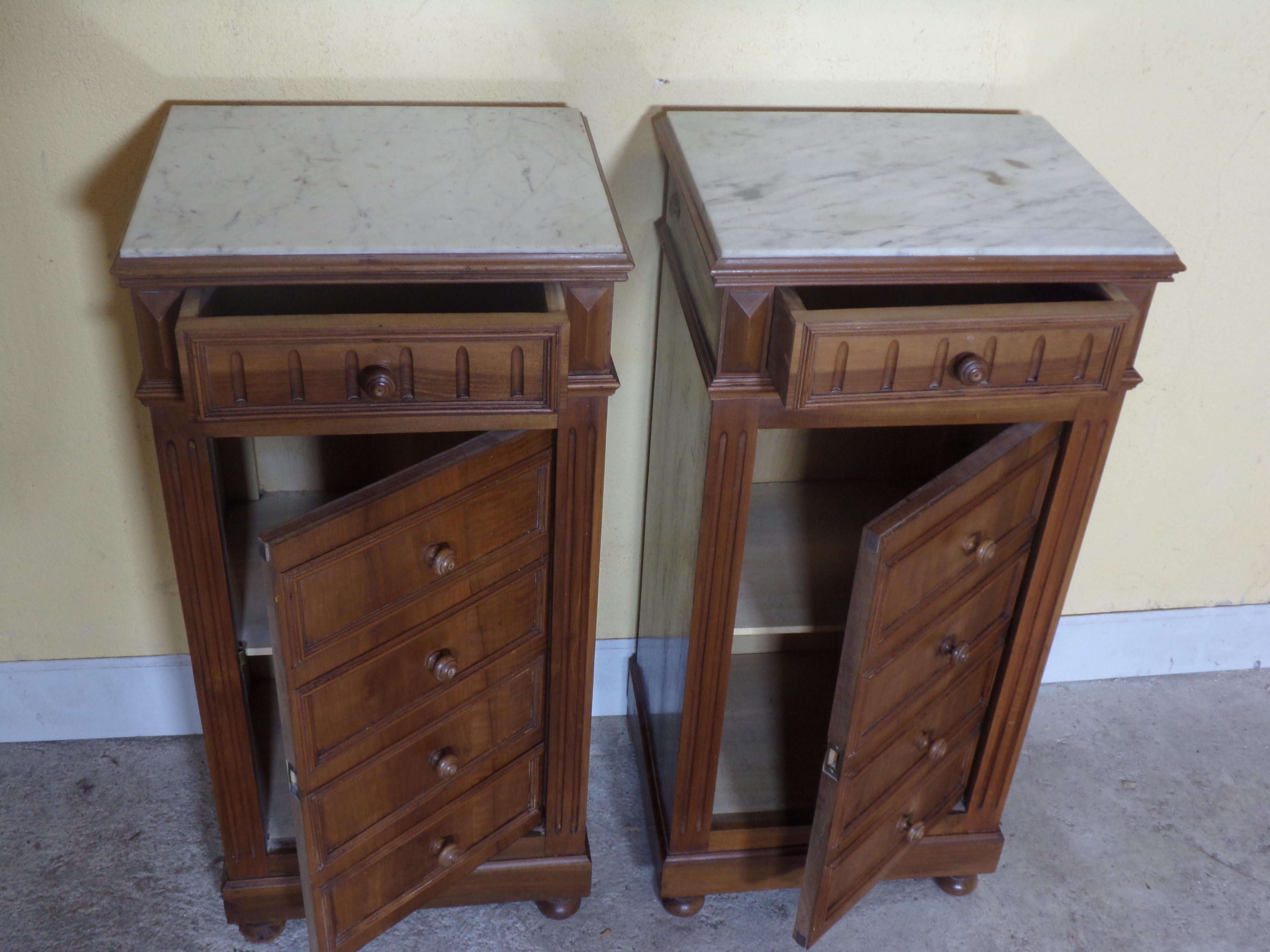 An unusual pair of walnut bedside cabinets with marble tops. The drawers apart from the top one are false and form a door enclosing a cupboard with a single shelf, these super cabinets would go just as well as end or occasional pieces in your living