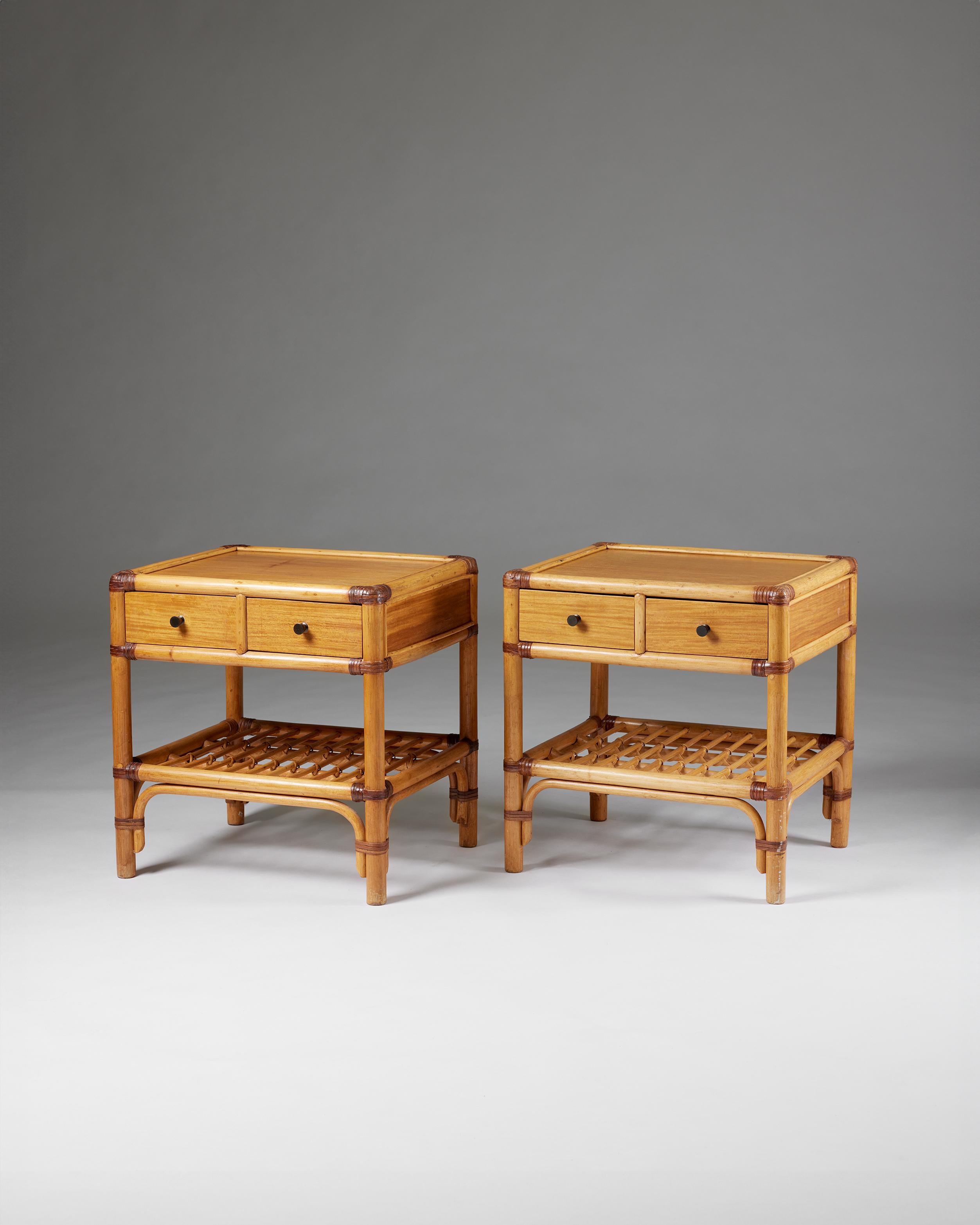 Pair of bedside tables, anonymous for DUX,
Sweden, 1960s.

Cane, rattan, teak and metal.

The colonial-style combination of bamboo, rattan, cane, and wood makes this Scandinavian bedside table design particularly interesting. The woven edges and