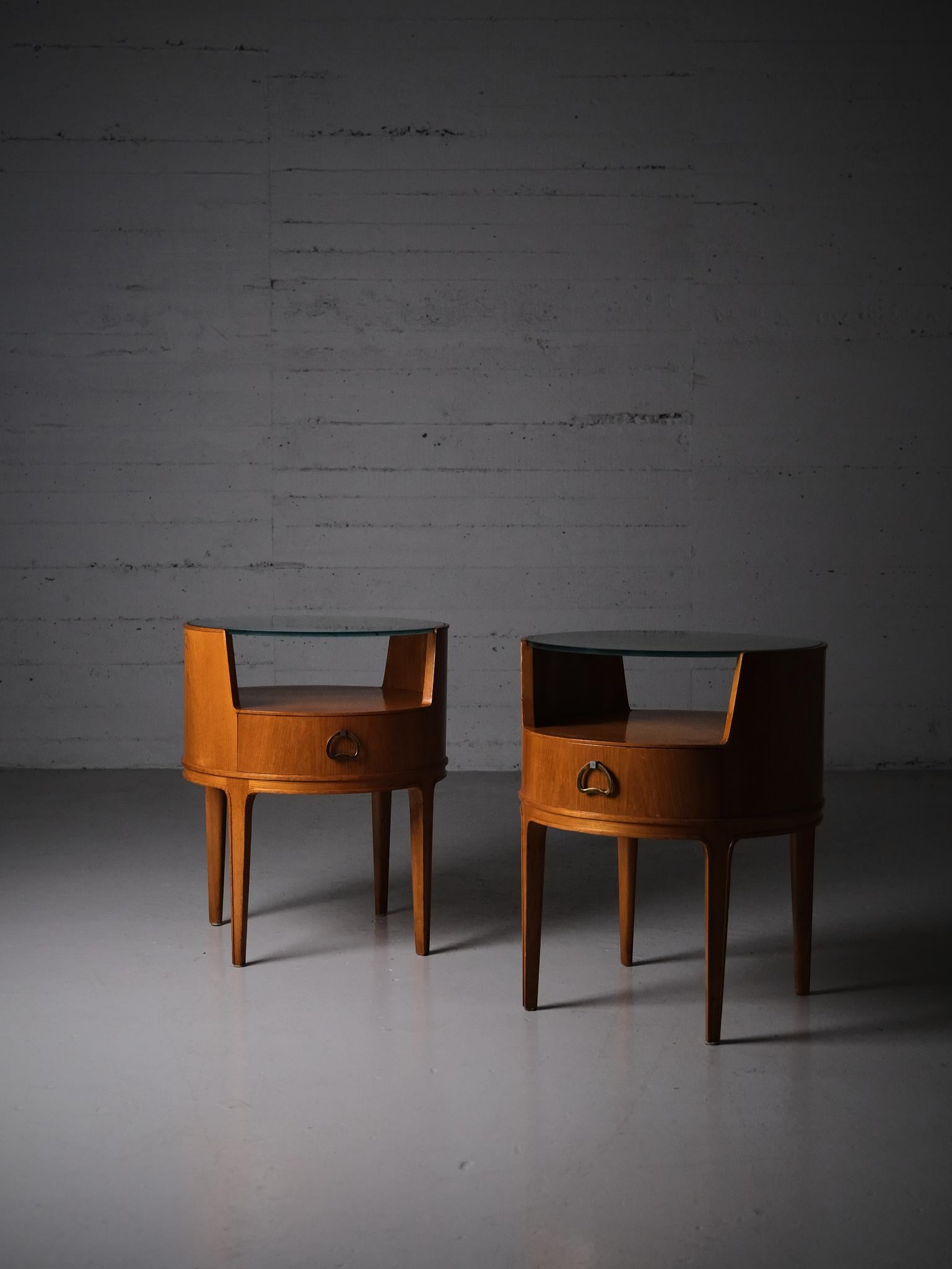 Precioso juego de mesillas de noche diseñado por Axel Larsson para Bodafors, Suecia, durante la década de 1940.

Forma circular con cuerpo realizado en olmo. Tapa de cristal con diseño a cuadros. Cajones con un escultural tirador de latón. 