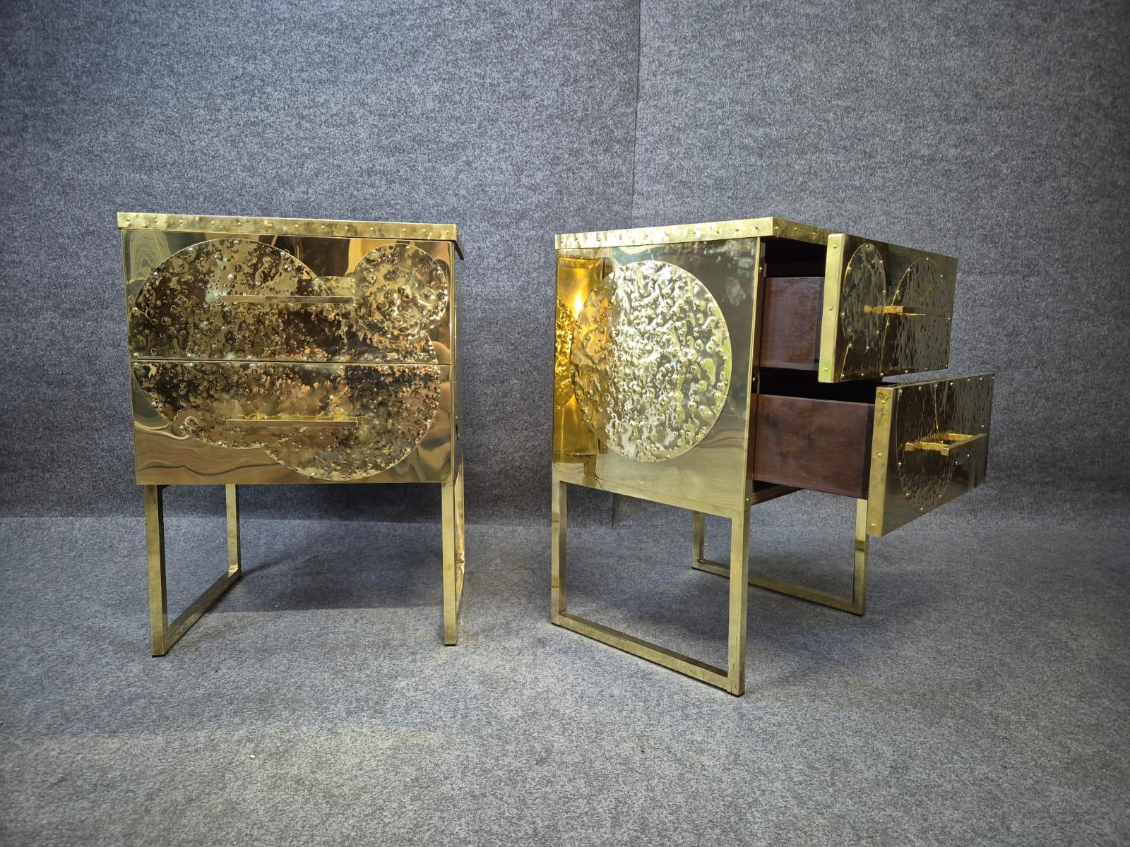 Coppia di comodini in ottone con piano in opalina nero e 2 cassetti.
I fianchi e il frontale sono decorati con elementi circolari in ottone martellato.
Interno rivestito di recente in velluto nero. 