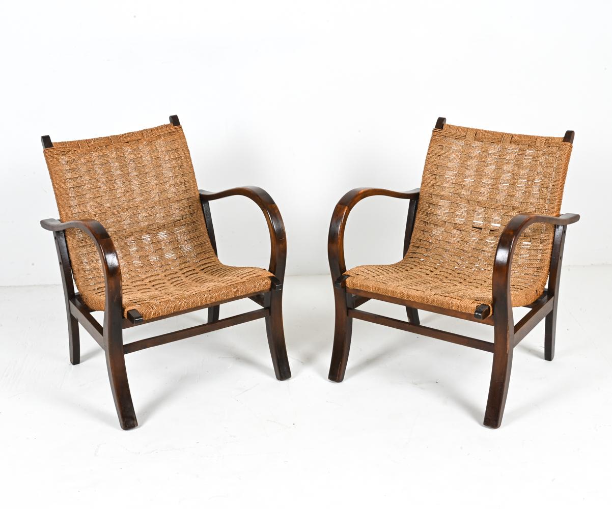 Recently imported from Europe, this mysterious pair of armchairs boasts a prestigious silhouette designed by Bauhaus architect Erich Dieckmann -with sensuous and dramatically curved frames of sculpted beech wood supporting continuous seats of woven