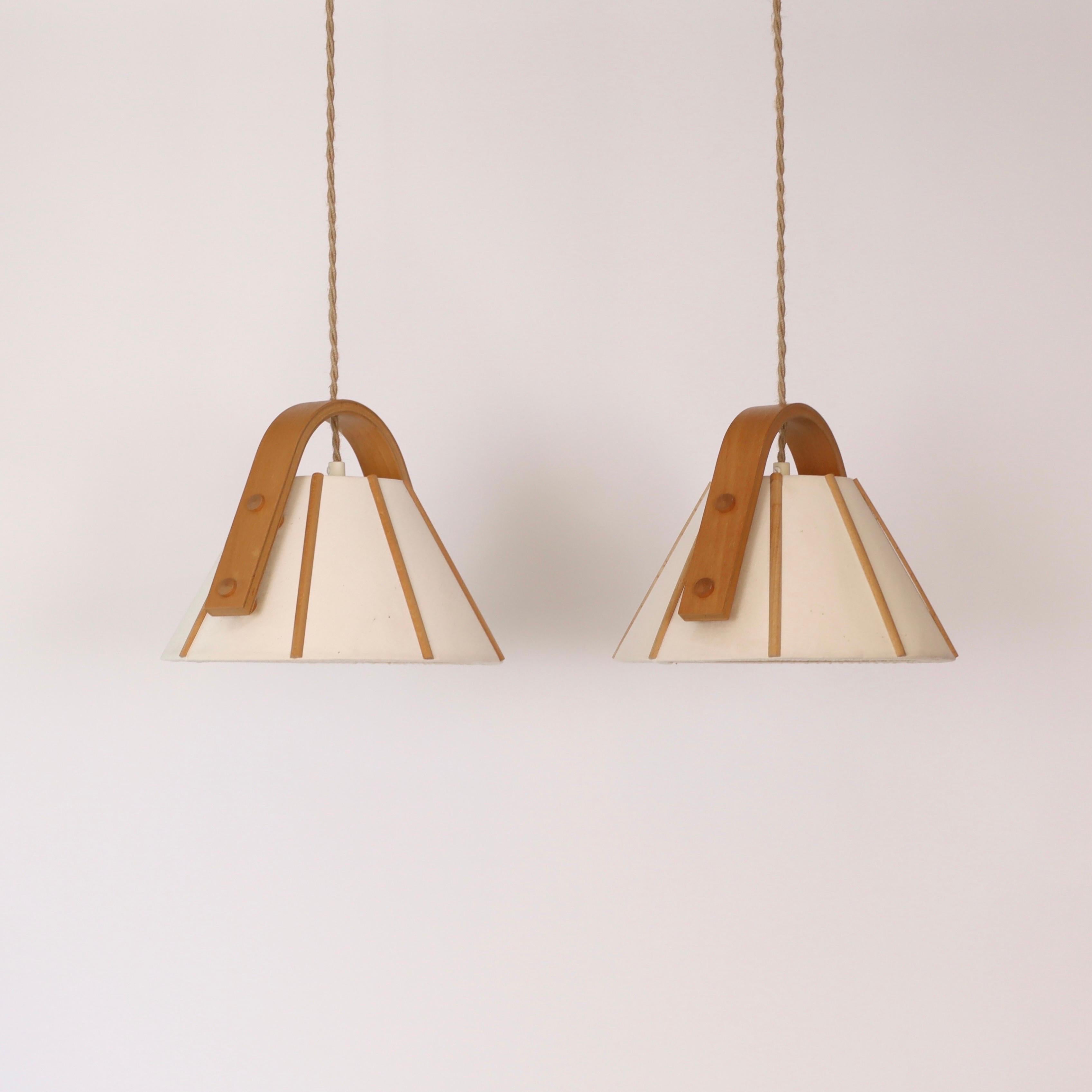 A pair of pendant lights in bend Beech wood with a Canvas shades designed by Jan Wickelgren in the 1970s for Aneta Sweden. A fine set for a beautiful place. 

* A pair (2) of pendant lights in bend beech veneer with beige canvas shades
* Designer: