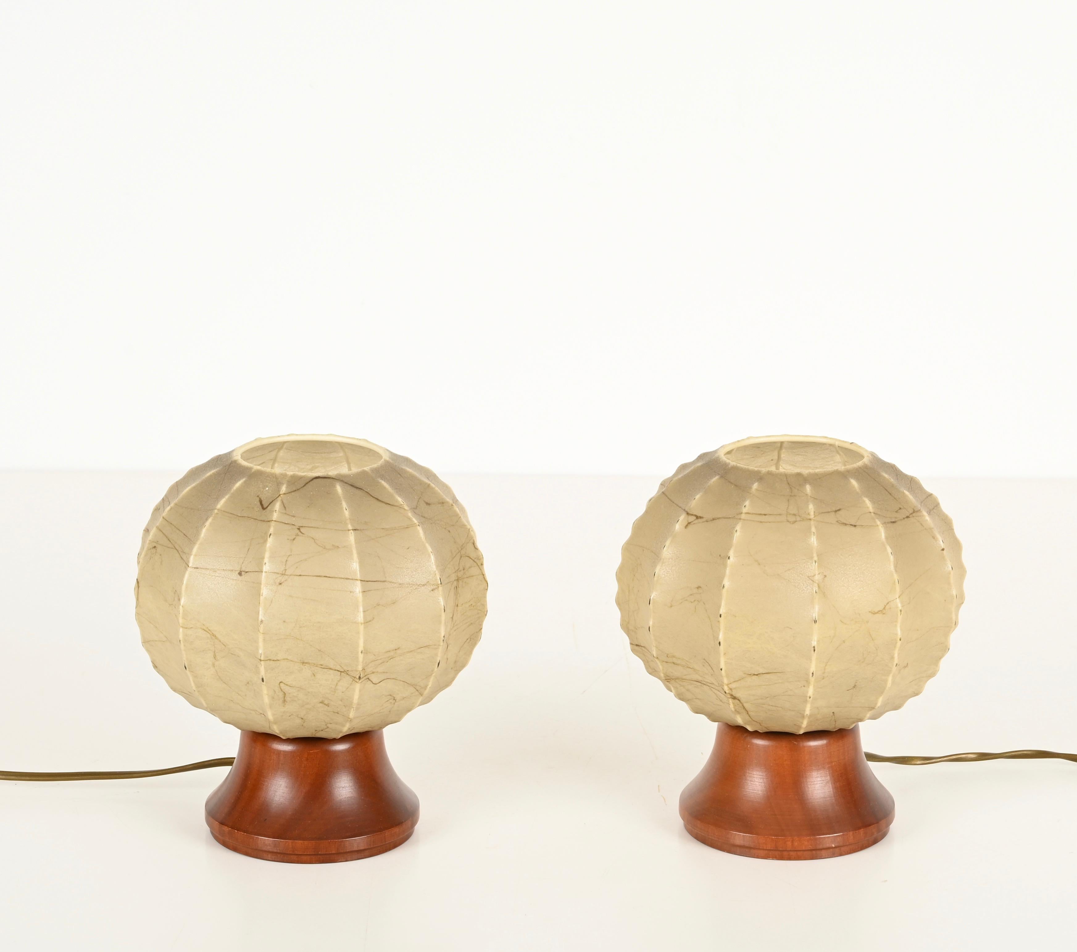 Merveilleuse et unique paire de lampes de table rondes en forme de cocon avec des bases en bois. En très bon état, sans déchirure ni tache. Ces lampes de table au charme incroyable ont été conçues par Achille Castiglioni et produites en Italie dans