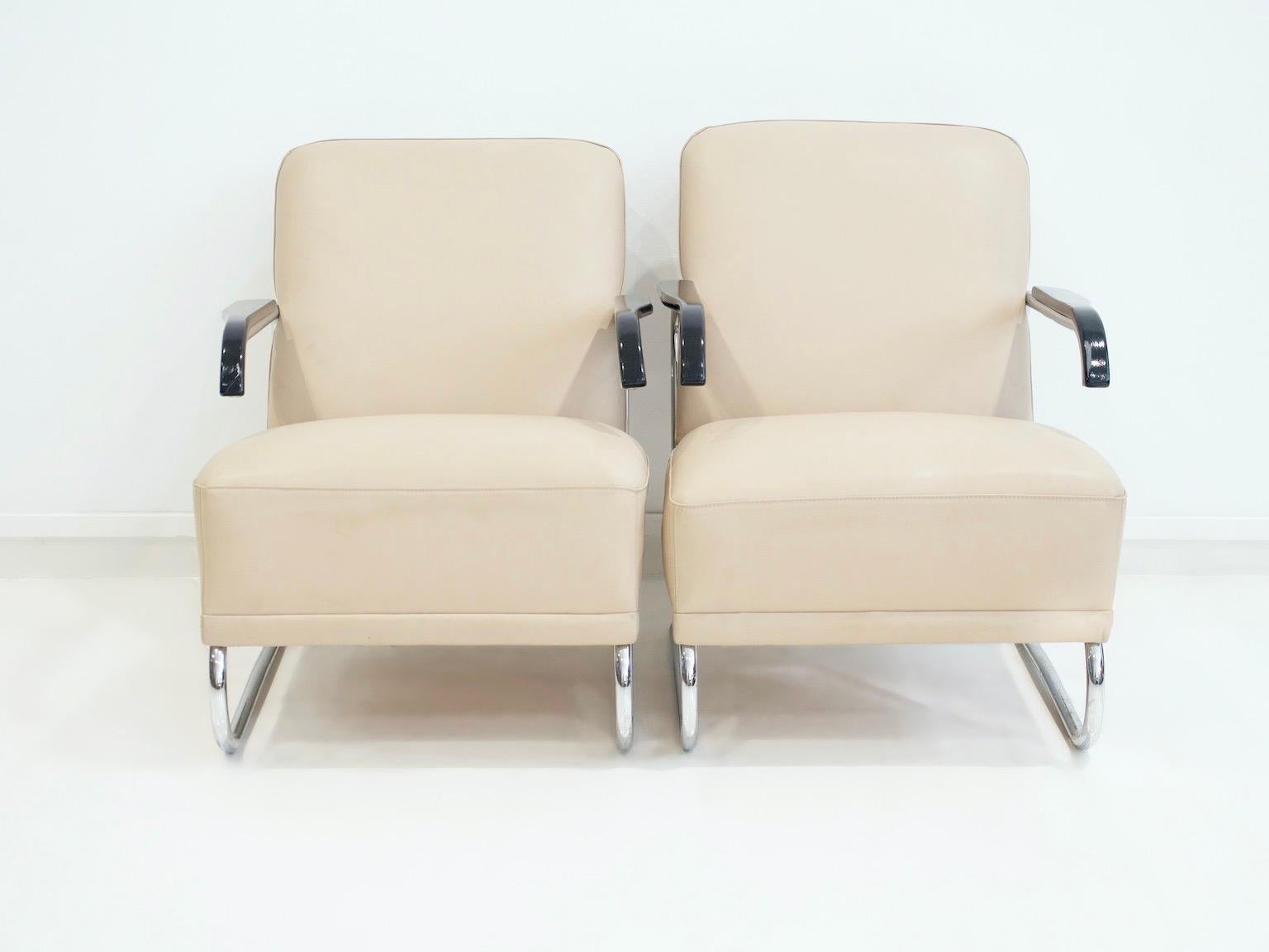 Pareja de tumbonas con armazón de tubo de acero cromado y reposabrazos de madera lacada en negro. Asiento y respaldo tapizados en piel beige claro. Asientos muy cómodos.
