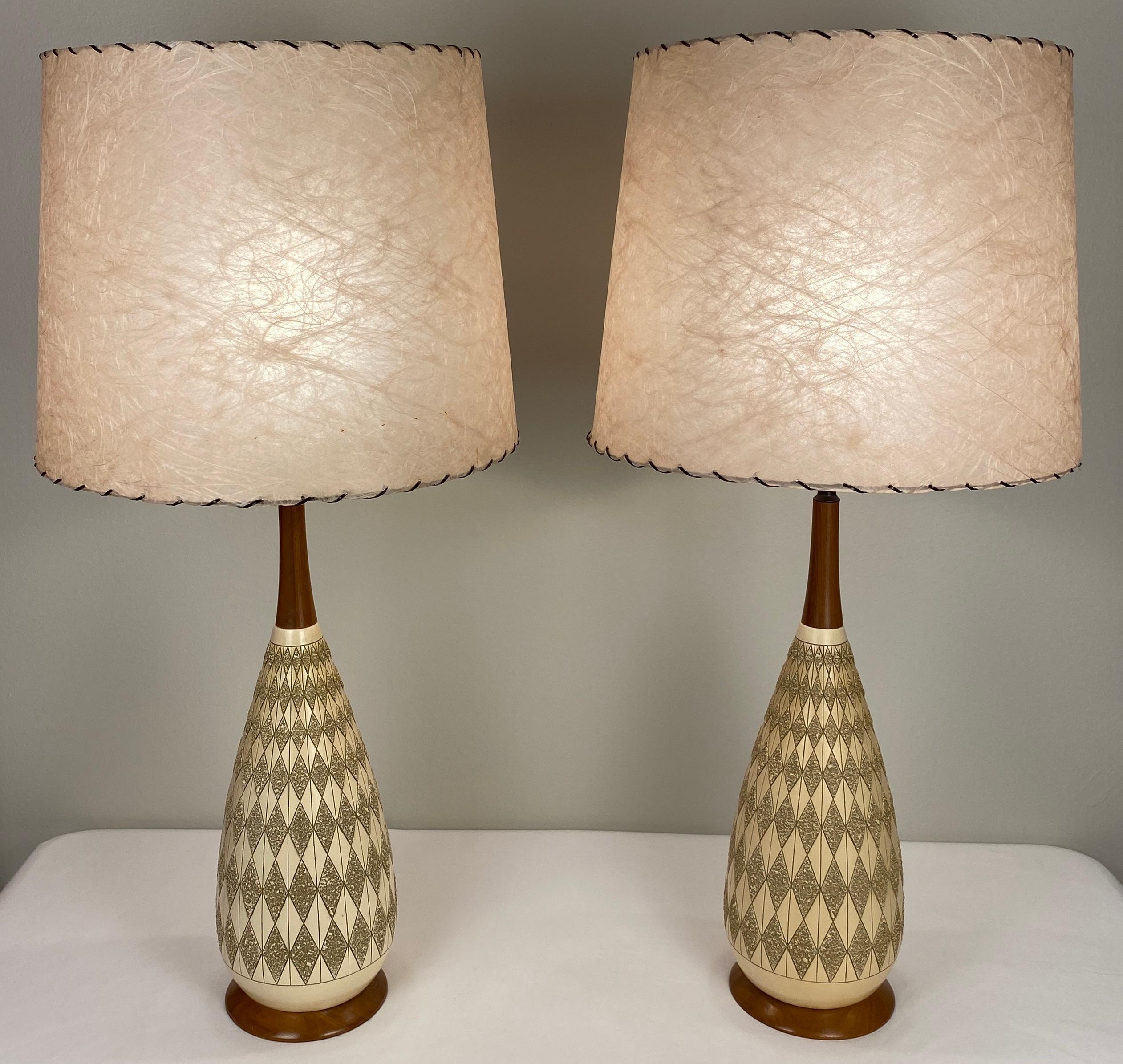 Pair of fine quality wooden mid-century table lamps with resin shades. 

These table lamps boasts curves that bring fluid movement into an otherwise straightforward design. It creates an almost optical illusion that recalibrates expectations of what