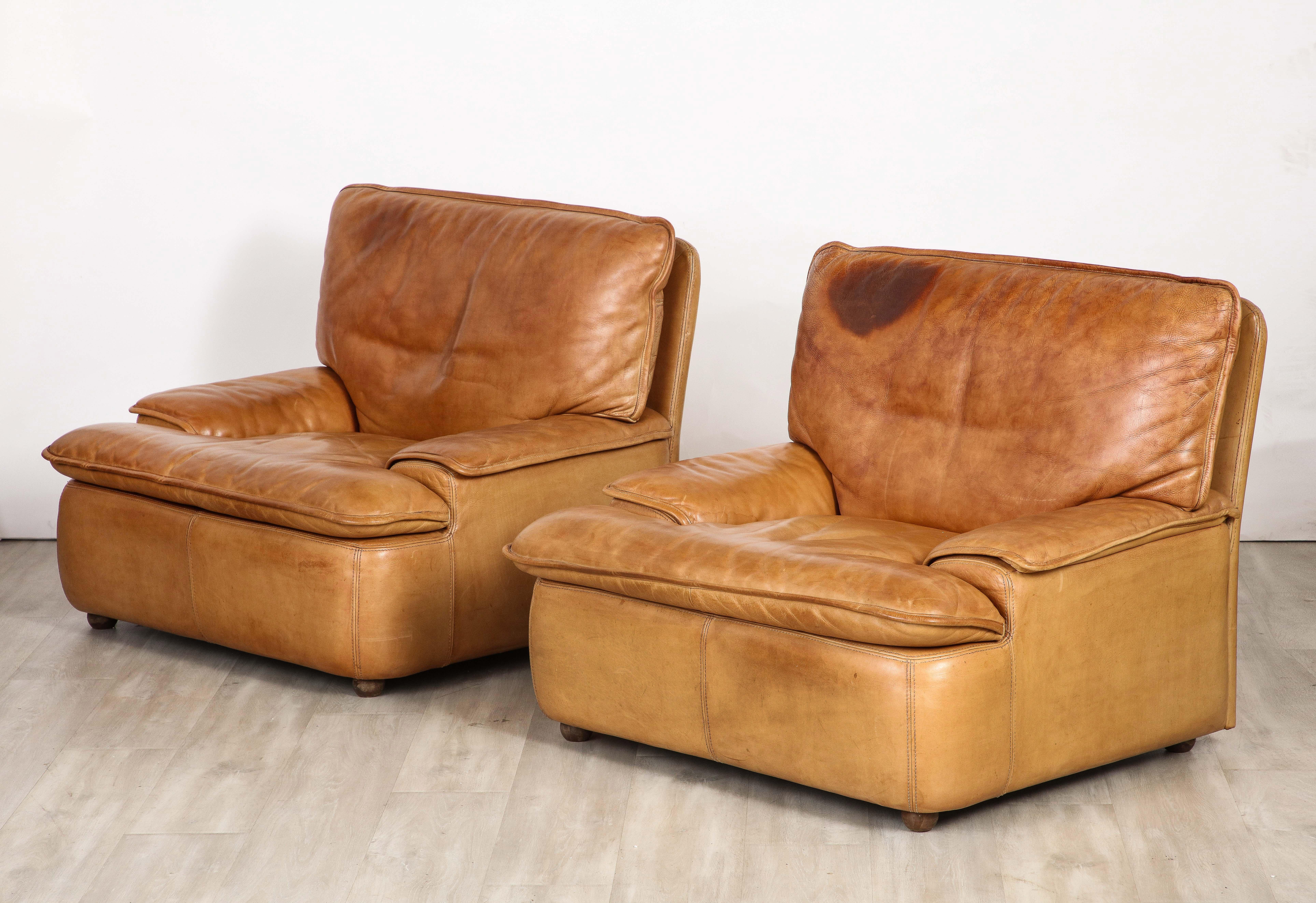 A pair of Belgian leather lounge chairs, with fantastic proportions and grand in scale.  All original caramel colored sumptuous leather with a rich patina; the seats, arm rests and back are kept into place with Velcro to secure a minimalist and