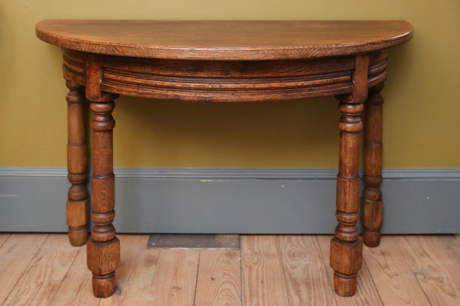 Pair of oak Demilune consoles: nice robust turning and proportion. Rustic or country in style, circa 1890-1930. Sold together as a pair. The oak has nice graining and the tables are simple and rustic.