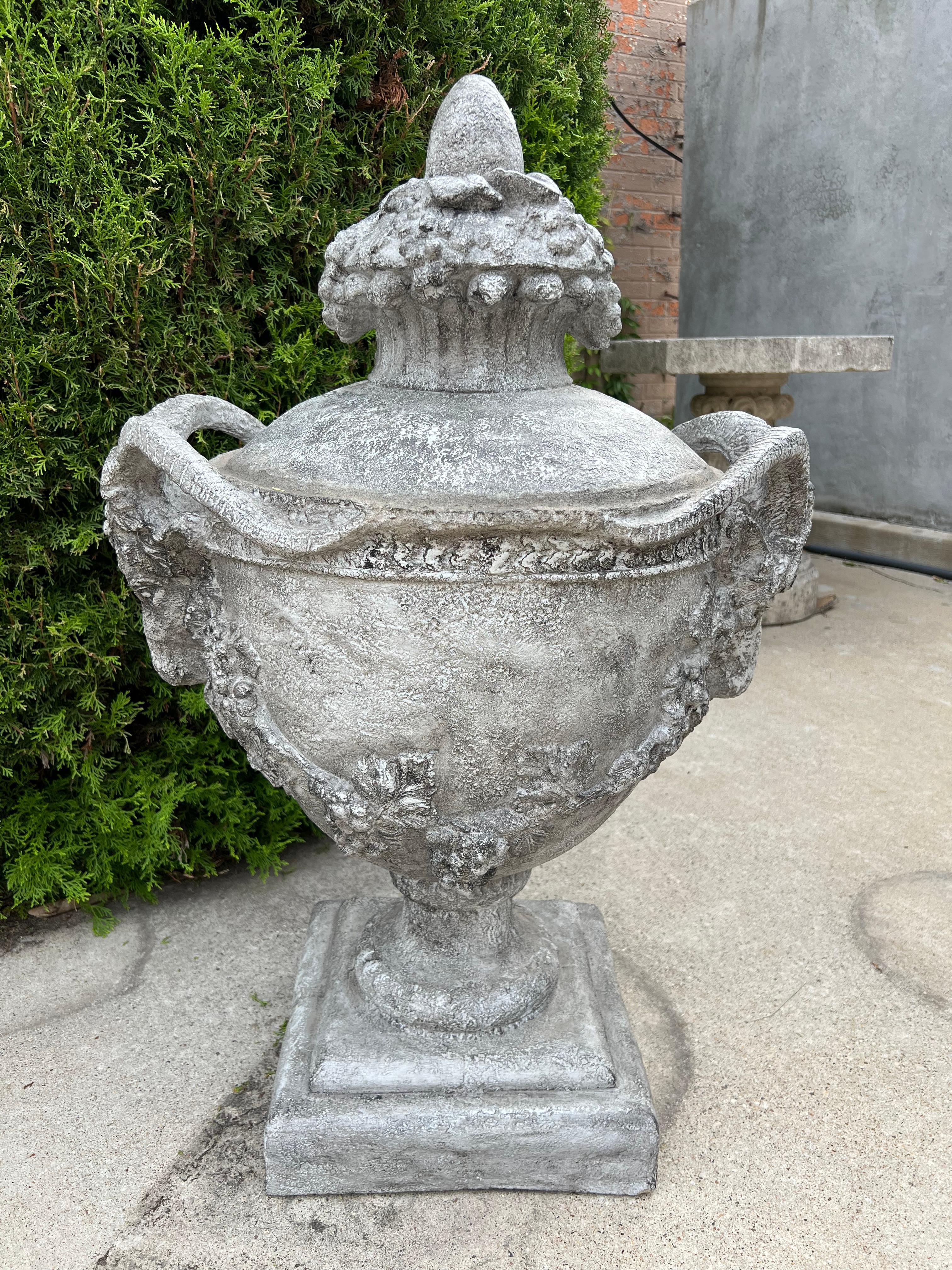 Ulteriori informazioni in arrivo...

Originaria del Belgio, questa coppia di urne da giardino in pietra fusa presenta elaborati manici a testa di ariete con corna esagerate che interrompono un anello di pula che circonda il corpo principale.  Sotto