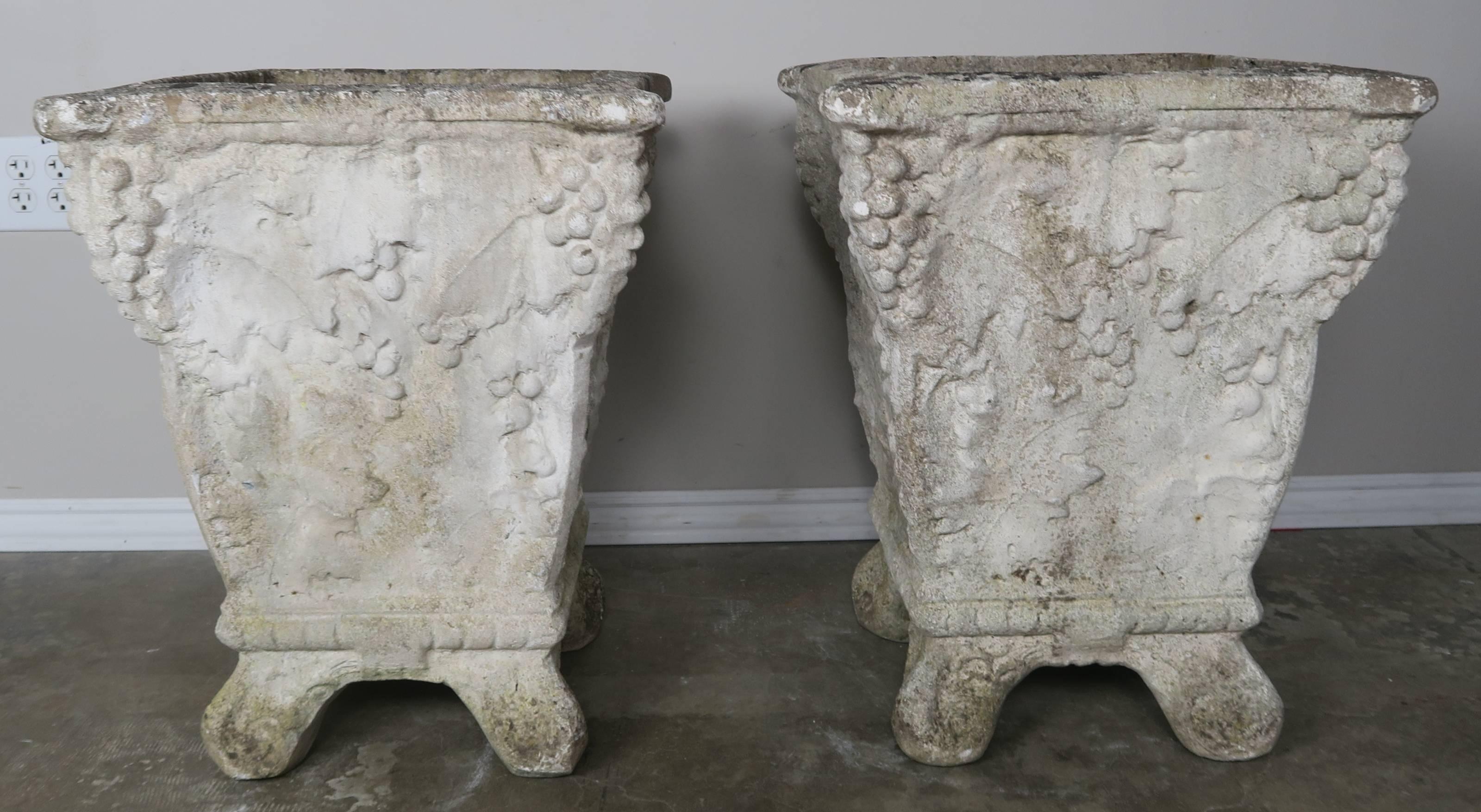 Pair of 1920s cast cement grape motif planters from Belgium. These planters have a rare interesting form and have developed a beautiful patina with some moss discoloration near the bottoms.