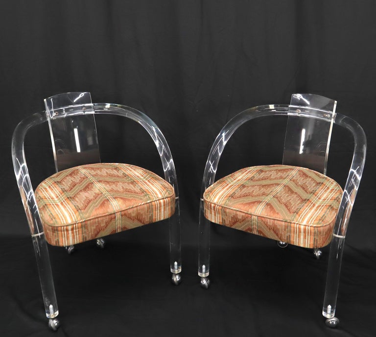 Pair of Mid-Century Modern upholstered seats lucite dining chairs on casters.