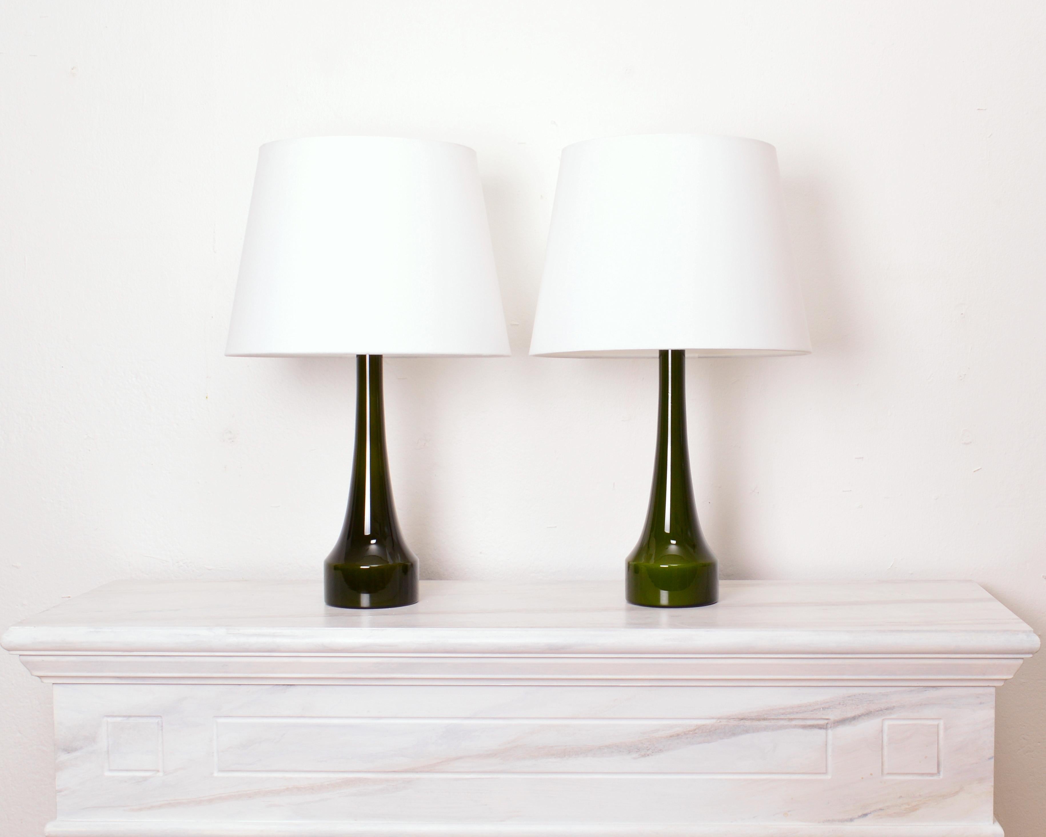 Set of two table lamps by Bergboms, Sweden 1960s. The lamps are made of glass and were manufactured by Holmegaard, Denmark. The design is simple and elegant with a slim waist and deep green color. Condition: Excellent vintage condition Measures: 36