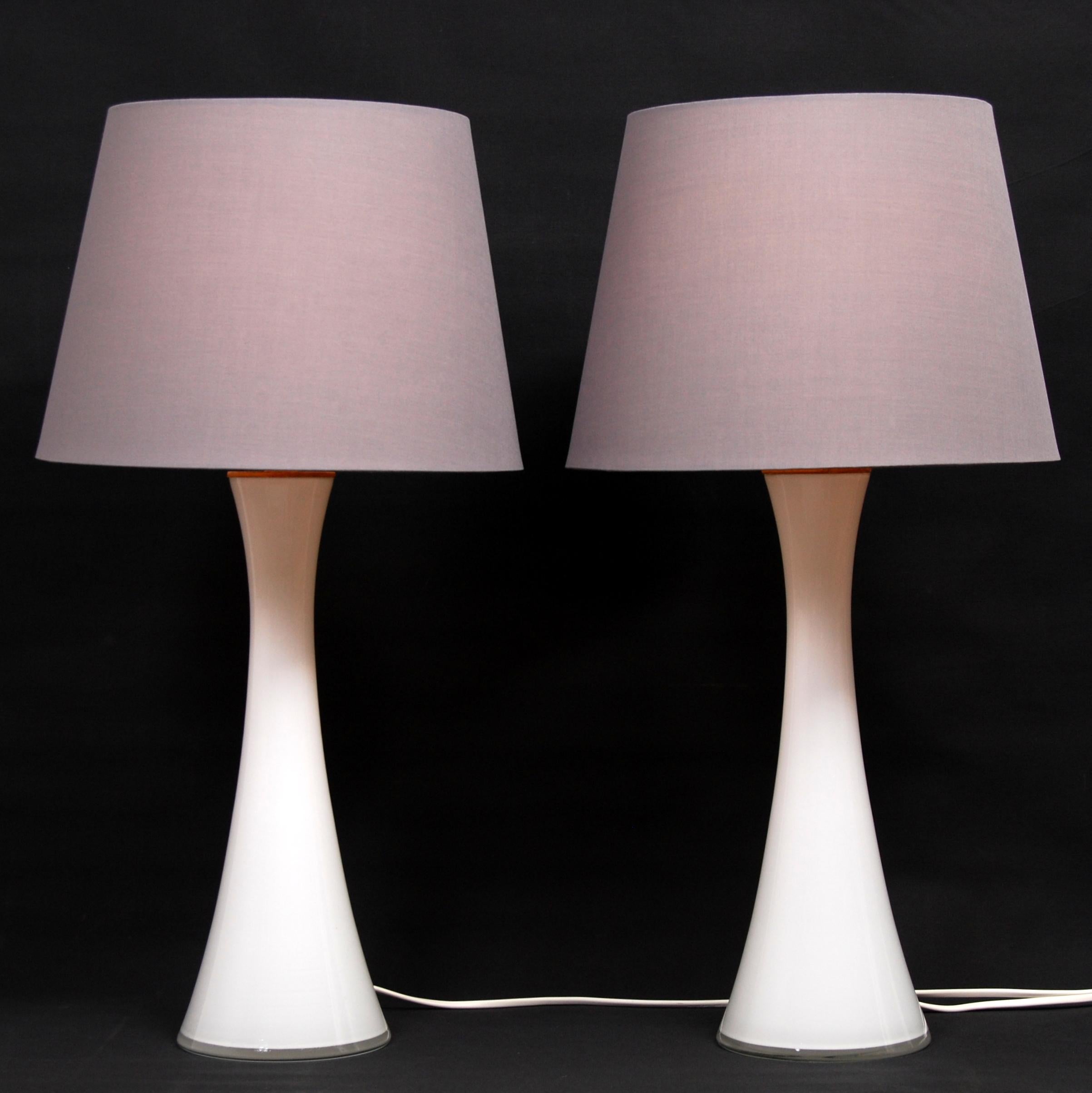 A pair of diabolo shaped Swedish opaline glass table lamps with teak fittings. Designed by Berndt Nordstedt for Bergboms. Newly Rewired. For sale without the two shades. The measurements and shipping costs stated are of the lamps without the shades.