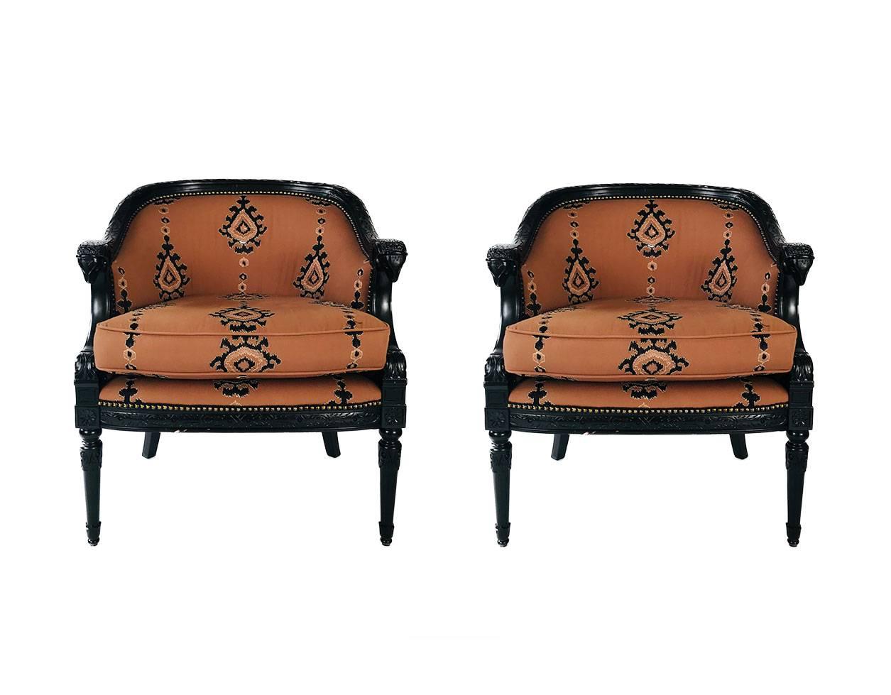 Contemporary pair of Louis XVI style tub chairs, recently recovered in a beautiful wool sateen with embroidered paisley finished with a nailhead detail. The lounge chairs feature beautiful black lacquer   carved ram-heads armrests. 

