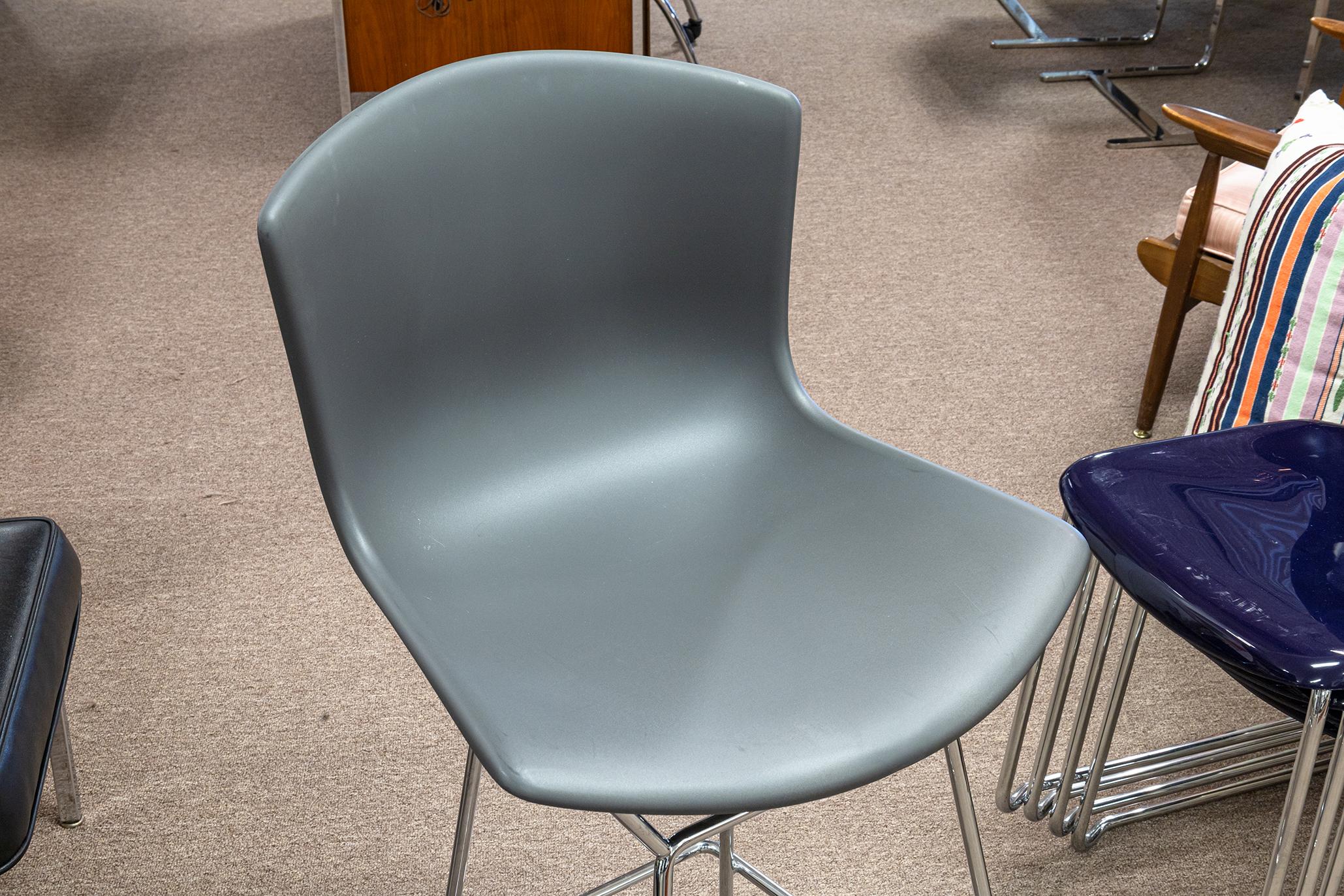 A pair of Bertoia for Knoll molded shell counter stools. A lovely pair of contemporary modern stools from Knoll's Bertoia collection. These two stools feature the iconic shell seat design in a muted grey color. They sit tall on rectangular chrome