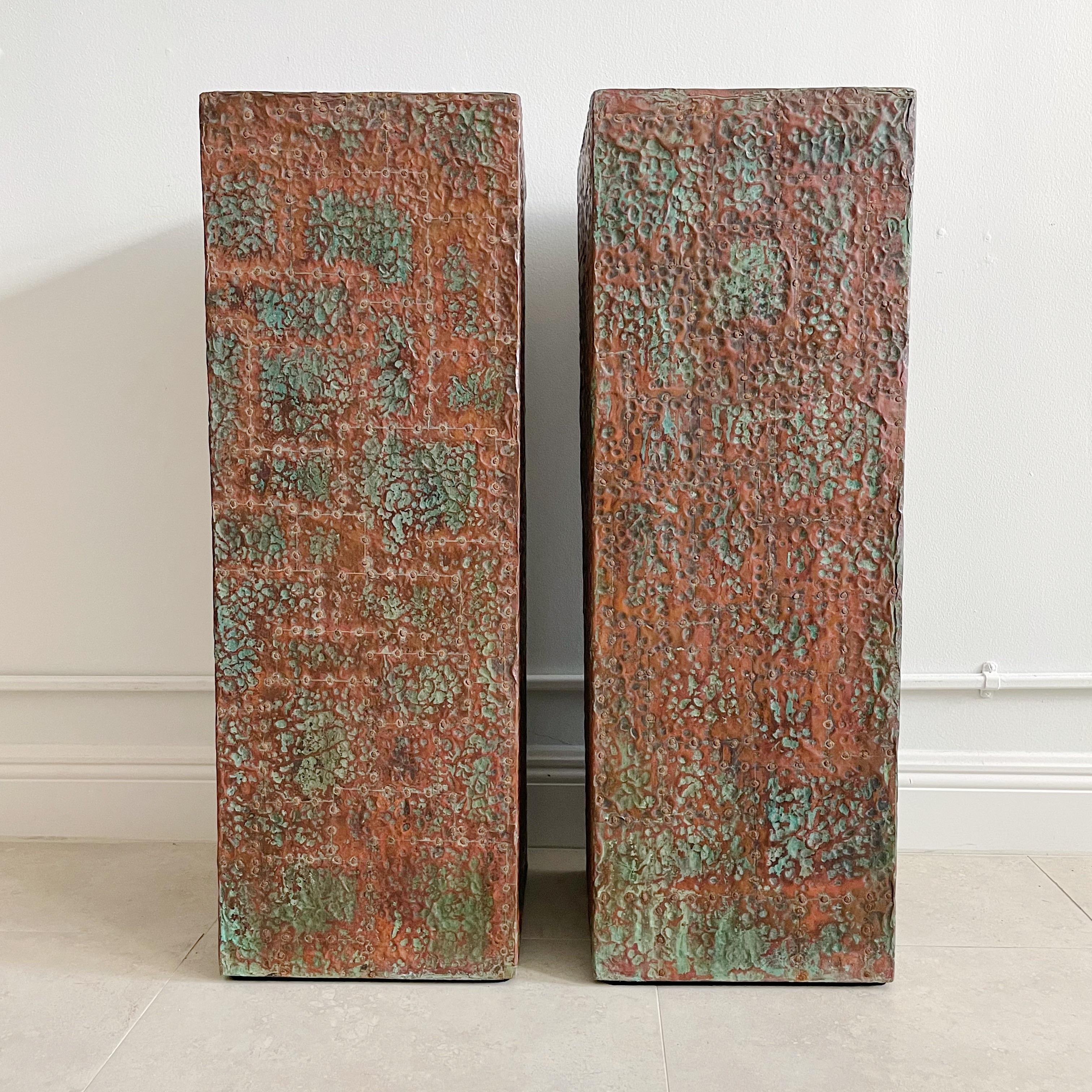 Custom wood pedestals in covered in hammered brutalist style copper. Square patchwork copper pieces with brass nailheads over wood.