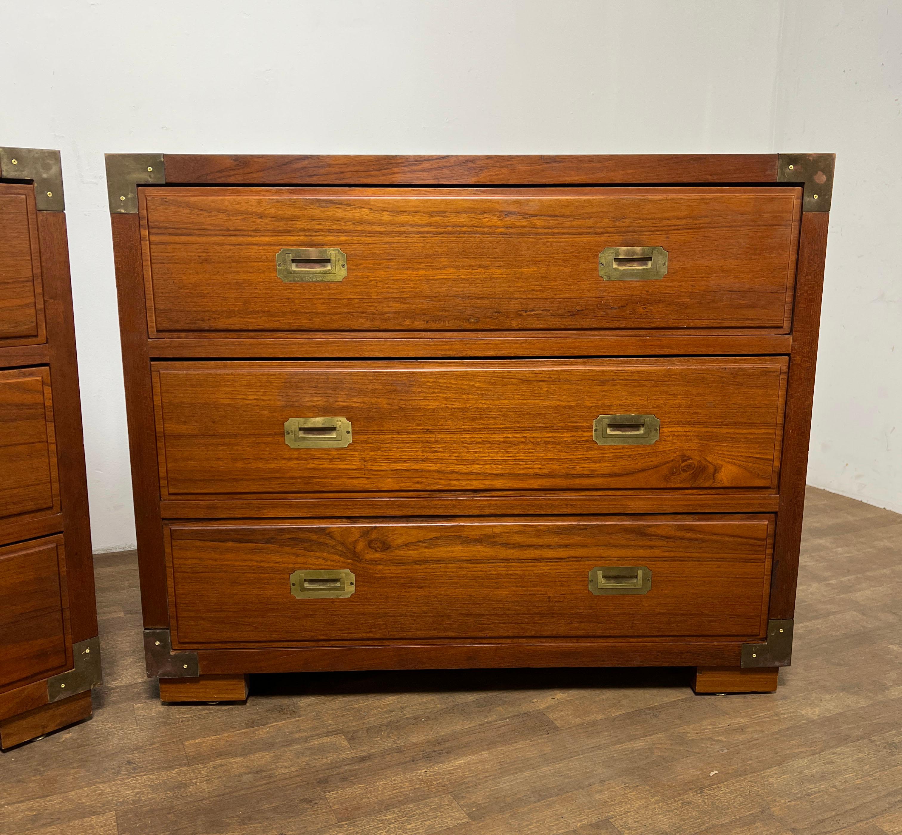 A bespoke pair of solid teak campaign style chests of three deep drawers, with flush mount brass handles and corner binding. Made in British Hong Kong, ca. 1950s.
