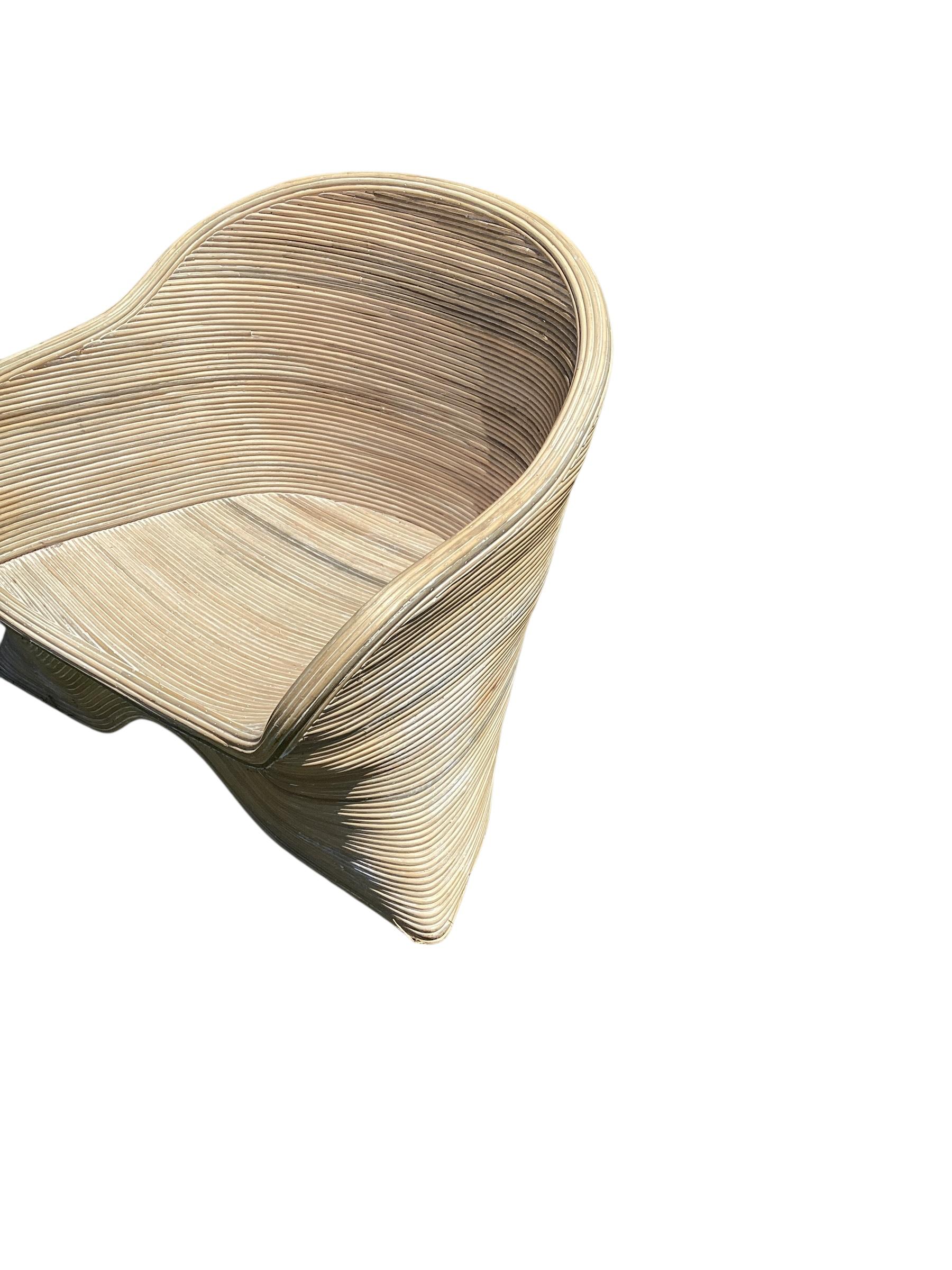 Paire de chaises basses en rotin fendu sculpté de Betty Cobonpue. En bon état avec quelques pertes de roseaux à la base des chaises.