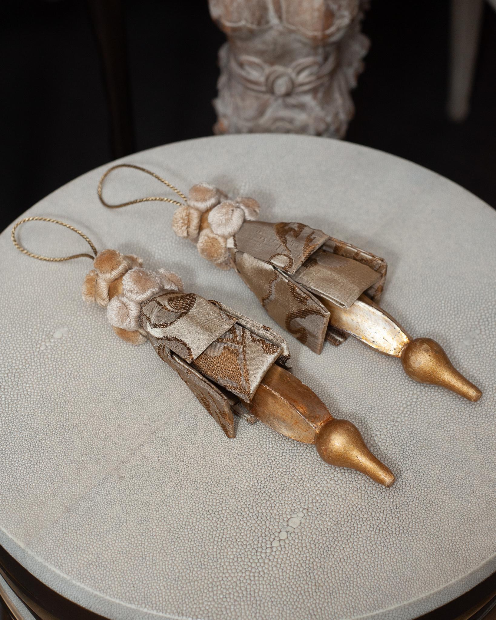 A gorgeous pair of hand carved gilt wood and silk damask tassels, from Bevilacqua Italy. Established by Luigi Bevilacqua, and operating out of Venice since 1875, Bevilacqua Tessuti produces the most exquisite handwoven fabrics available out of