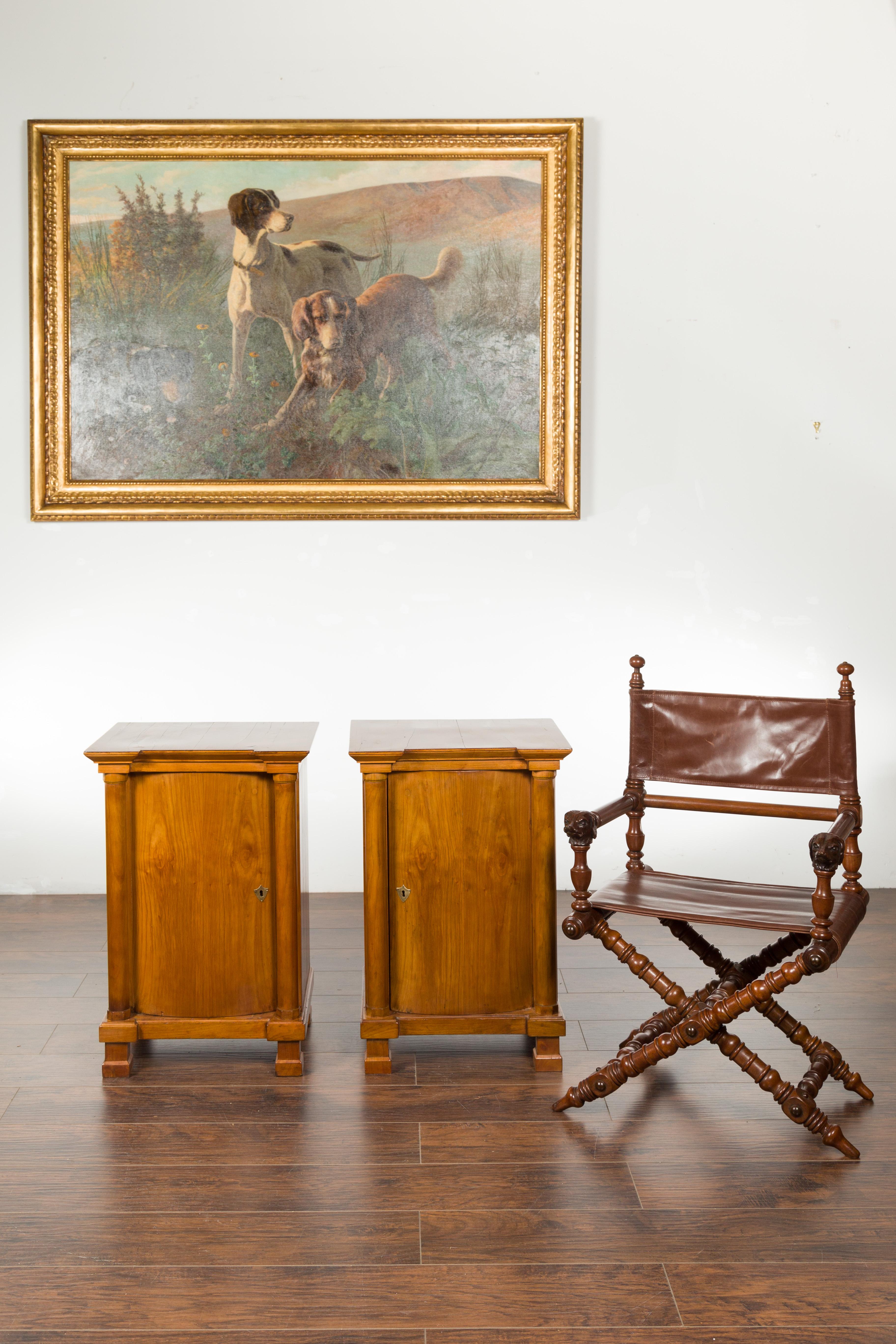 A pair of Biedermeier period walnut cabinets from the mid 19th century, with single door and semi-columns. Created in Austria during the second quarter of the 19th century, each of this pair of Biedermeier cabinets features a rectangular top with