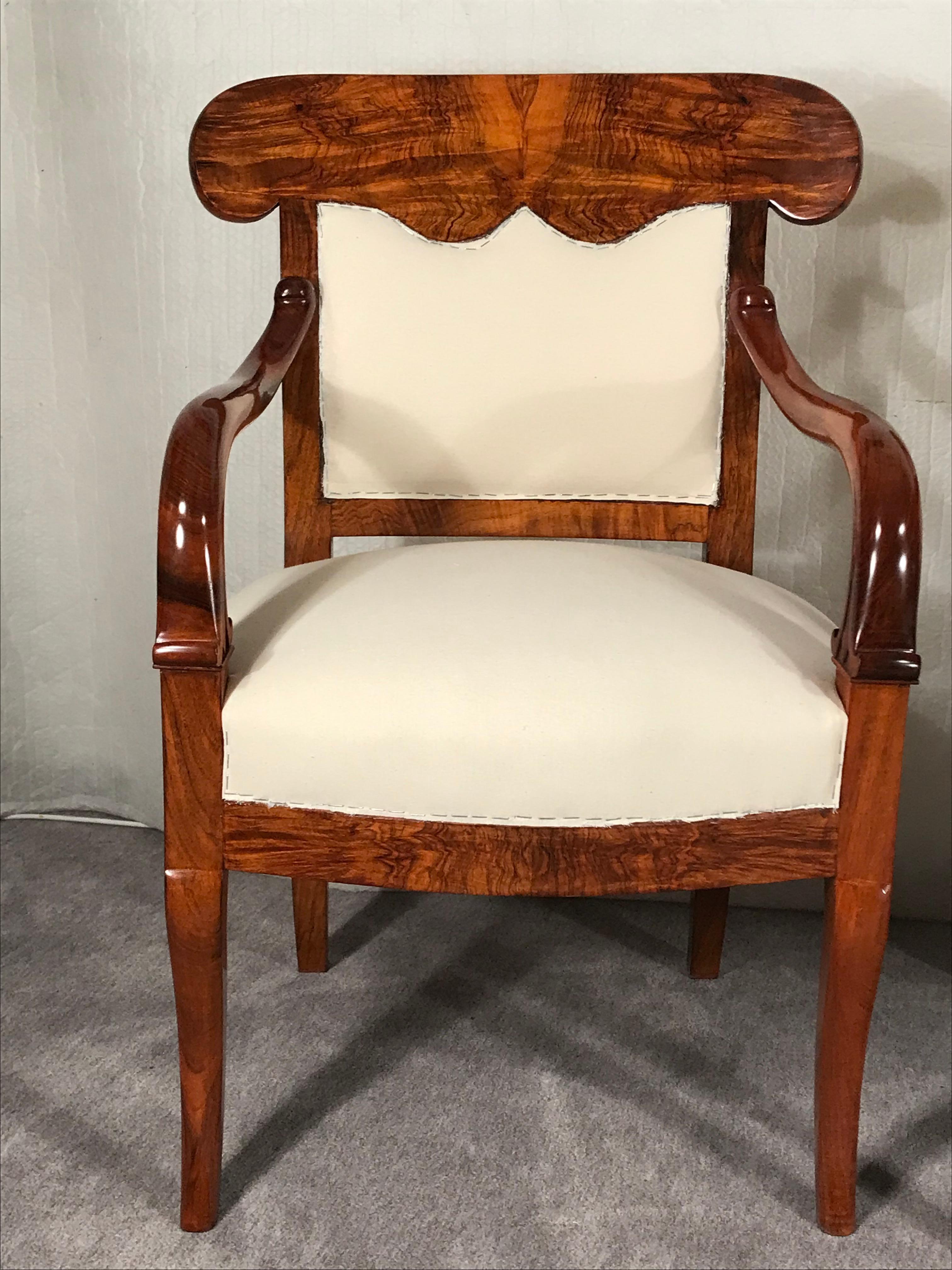 Pair of Biedermeier armchairs, South German 1820. 
This unique pair of Biedermeier armchairs has a gorgeous walnut veneer. They have very pretty hand-carved details on the armrests. 
The chairs come expertly refinished and shellack hand-polished.