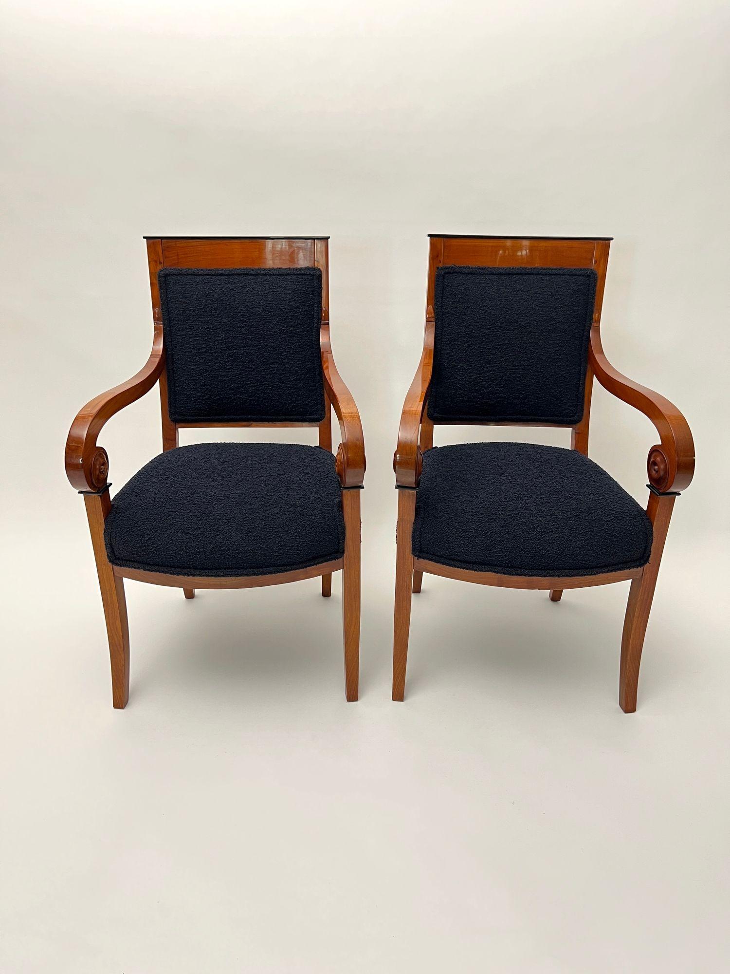 Elegant pair of Biedermeier / french restoration armchairs or salon chairs from France around 1820.
Solid cherry wood and veneered. Curved armrests with rosaces on the sides as decorative elements
Newly upholstered and covered with black boucle