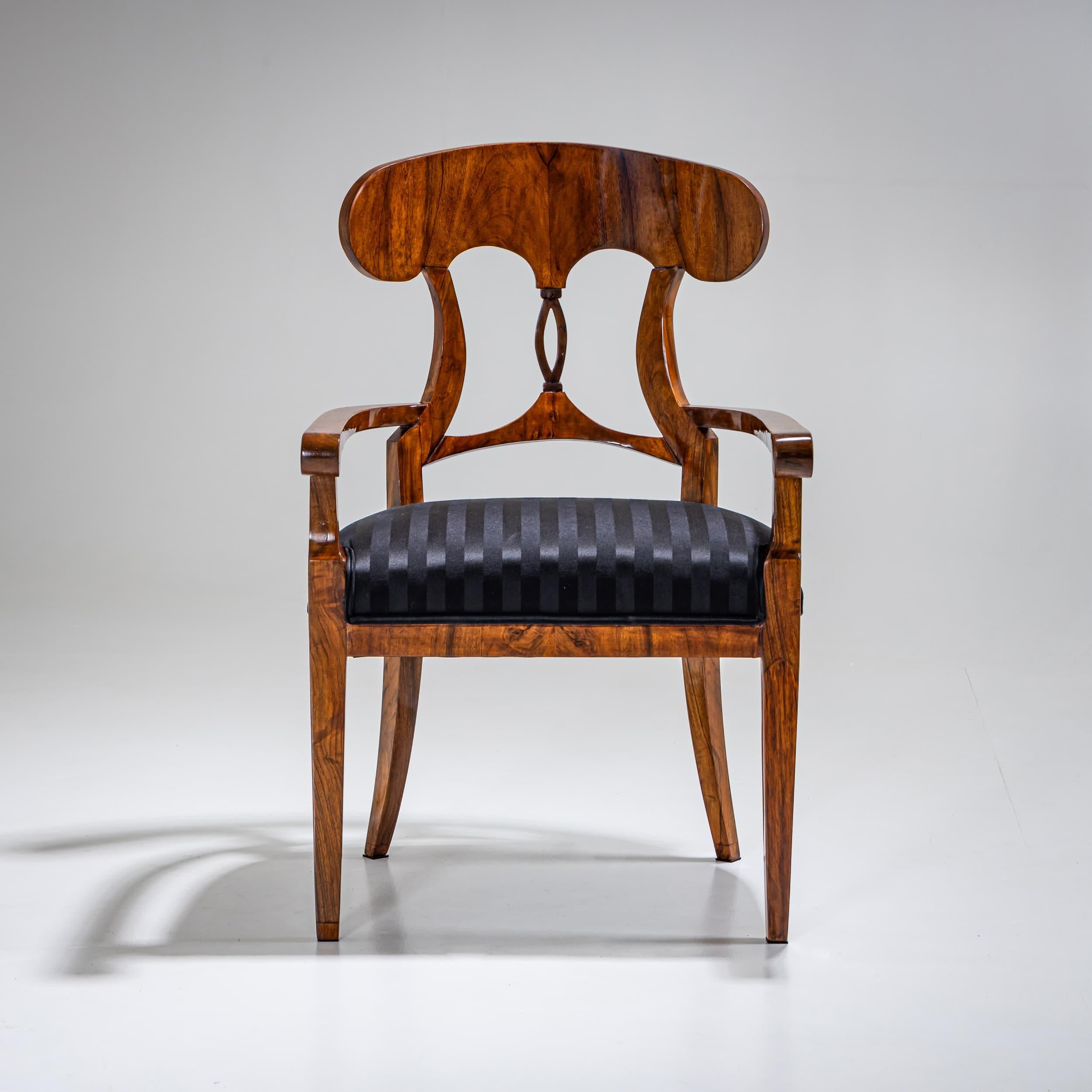 Pair of armchairs raised on tapered square legs with slightly splayed rear supports with straight aprons and armrests that terminate in stylized volutes. The finely crafted backrest features an openwork central splat and a shovel-shaped crest. The