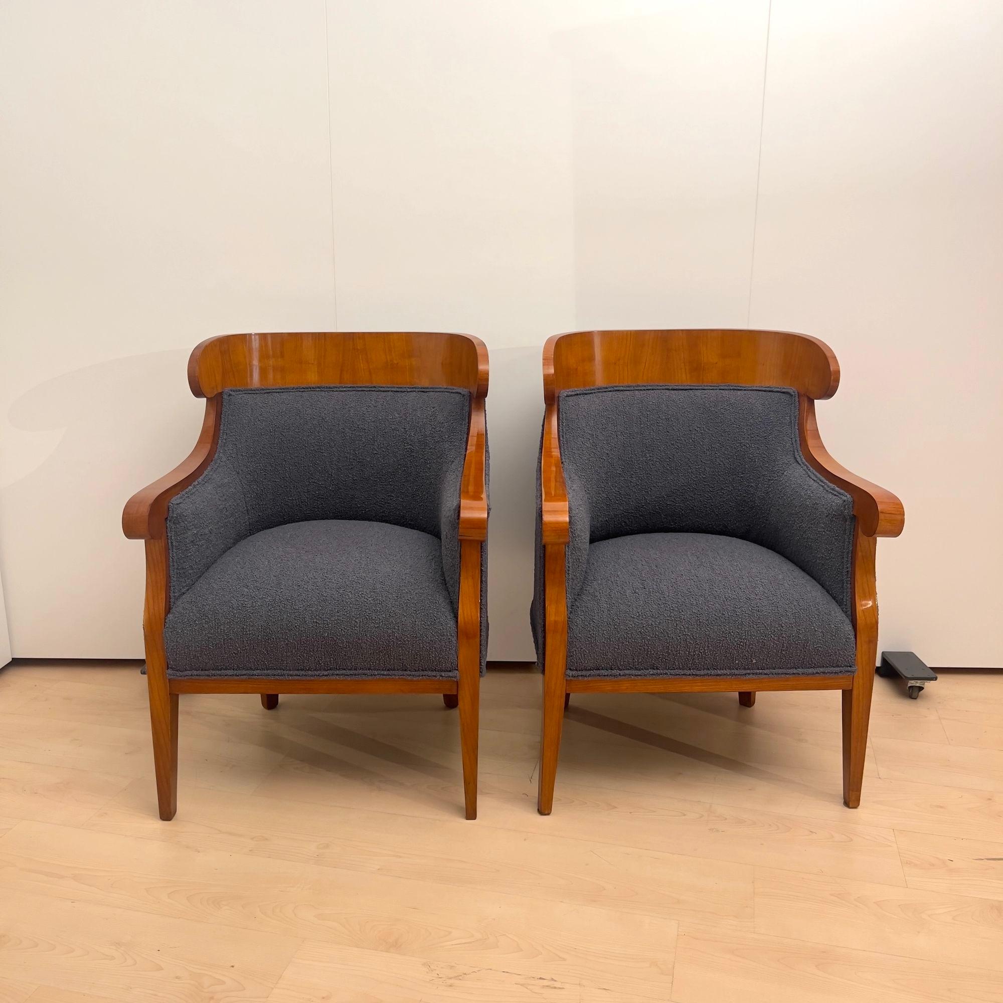 Elegant Pair of Biedermeier Bergere chairs from Austria around 1830.
Cherry wood veneered and solid. Square tapered legs.
Newly upholstered and covered with dark gray, slightly blueish boucle fabric.
Restored and hand-polished with