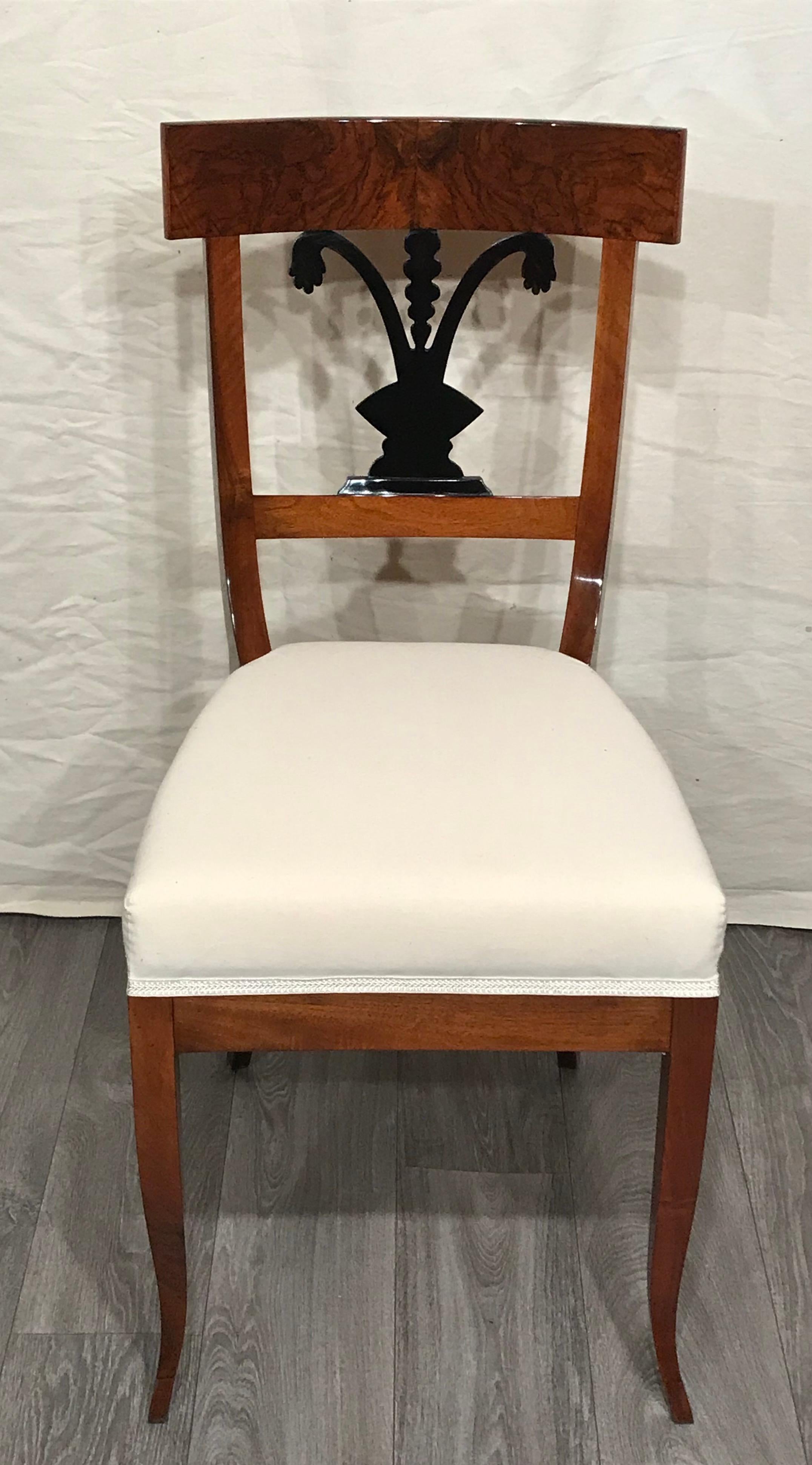 This beautiful pair of Biedermeier chairs comes newly refinished and with a new upholstery. The chairs date back to 1820 and come from Southern Germany. The walnut chairs have a beautiful designed back with ebonized details. 