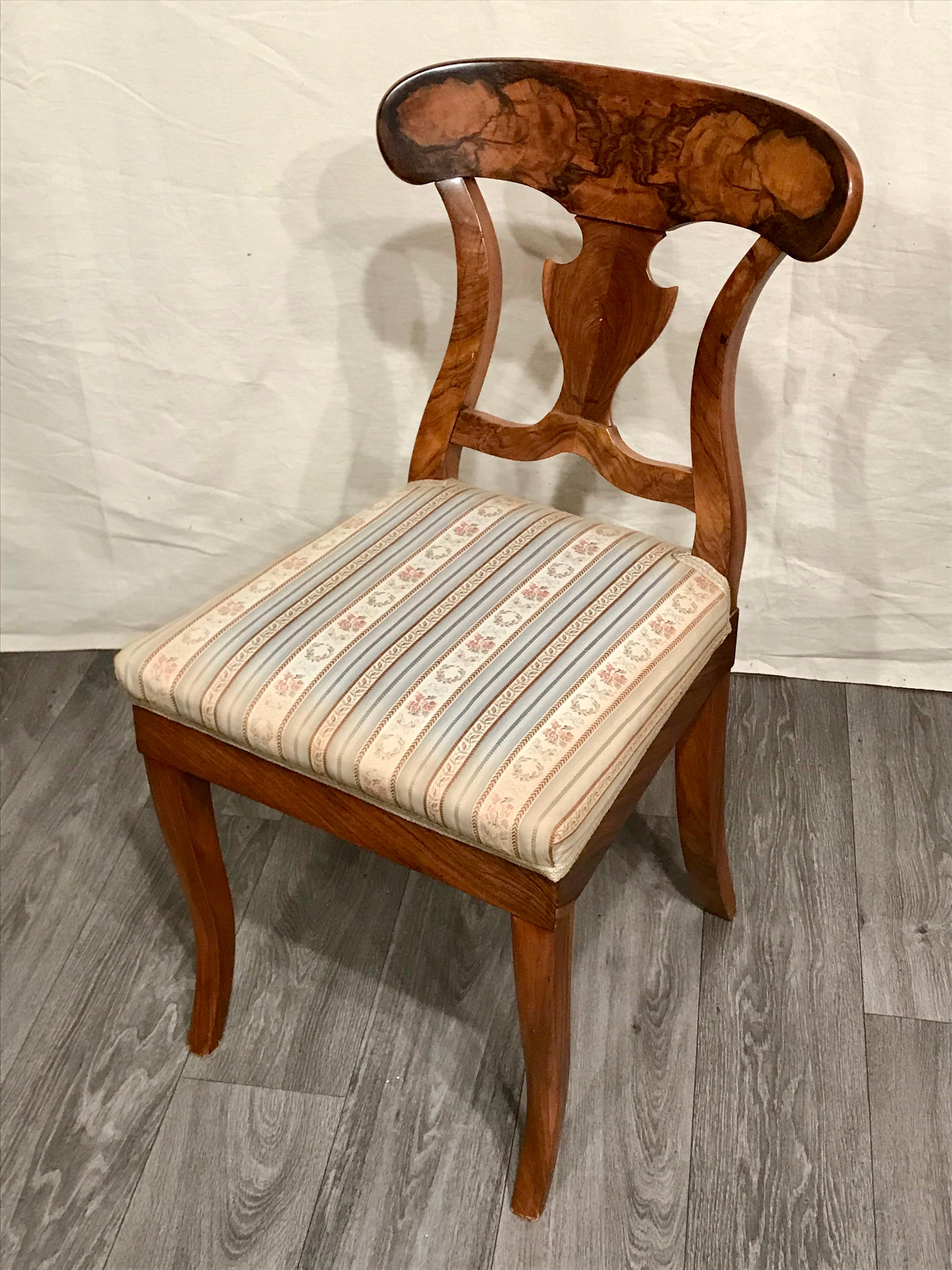Pair of Biedermeier chairs, South West Germany 1820, walnut veneer.
Original pair of Biedermeier chairs with a nicely designed back which features a beautiful walnut veneer grain. 
The chairs are in good original condition. On the bottom of the
