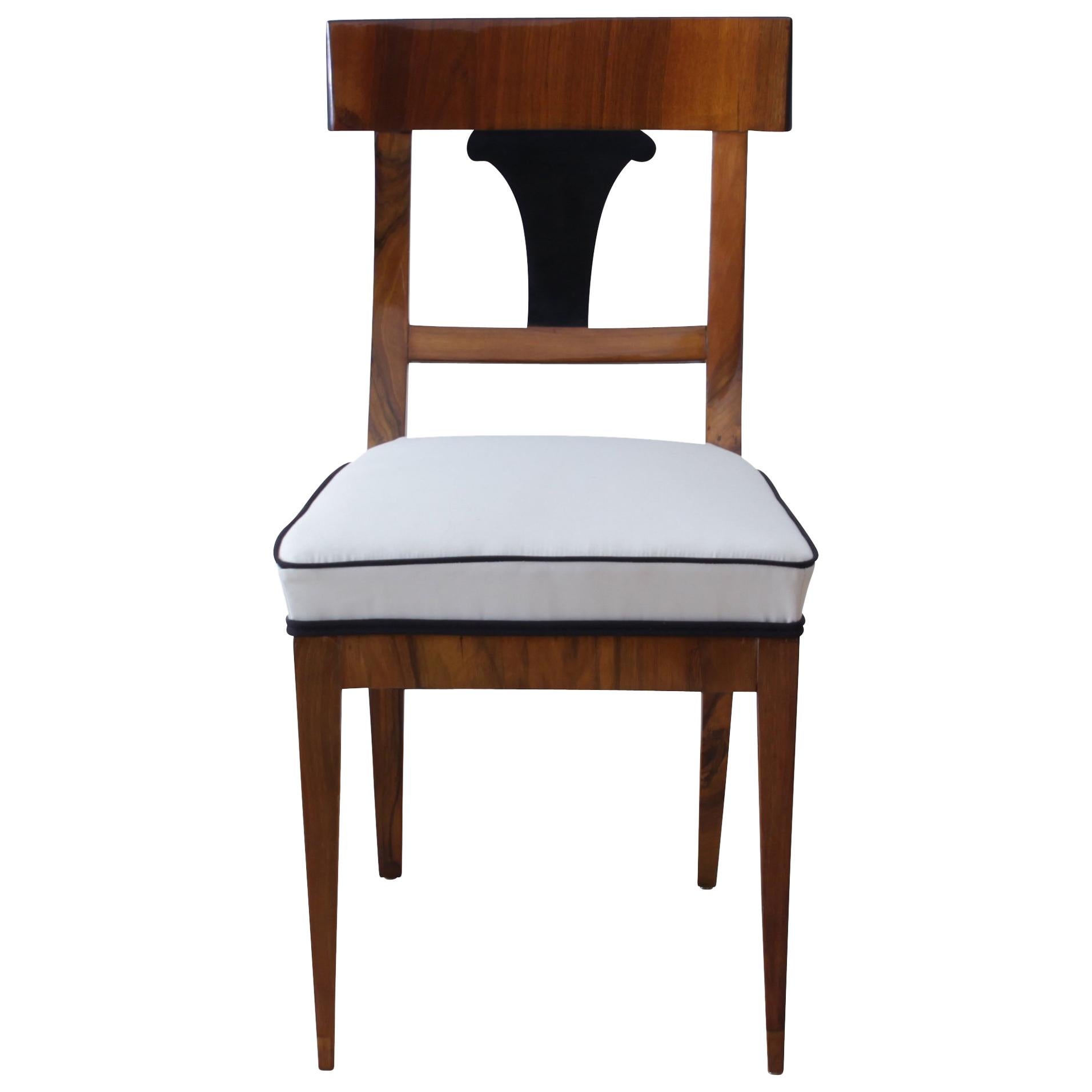 Very classic, early Biedermeier chair made of walnut solid wood and book-matched walnut veneer on the back rest. The back decor is ebonized wood.

While the front legs are running conical to the floor, the rear legs are elegantly curved to the