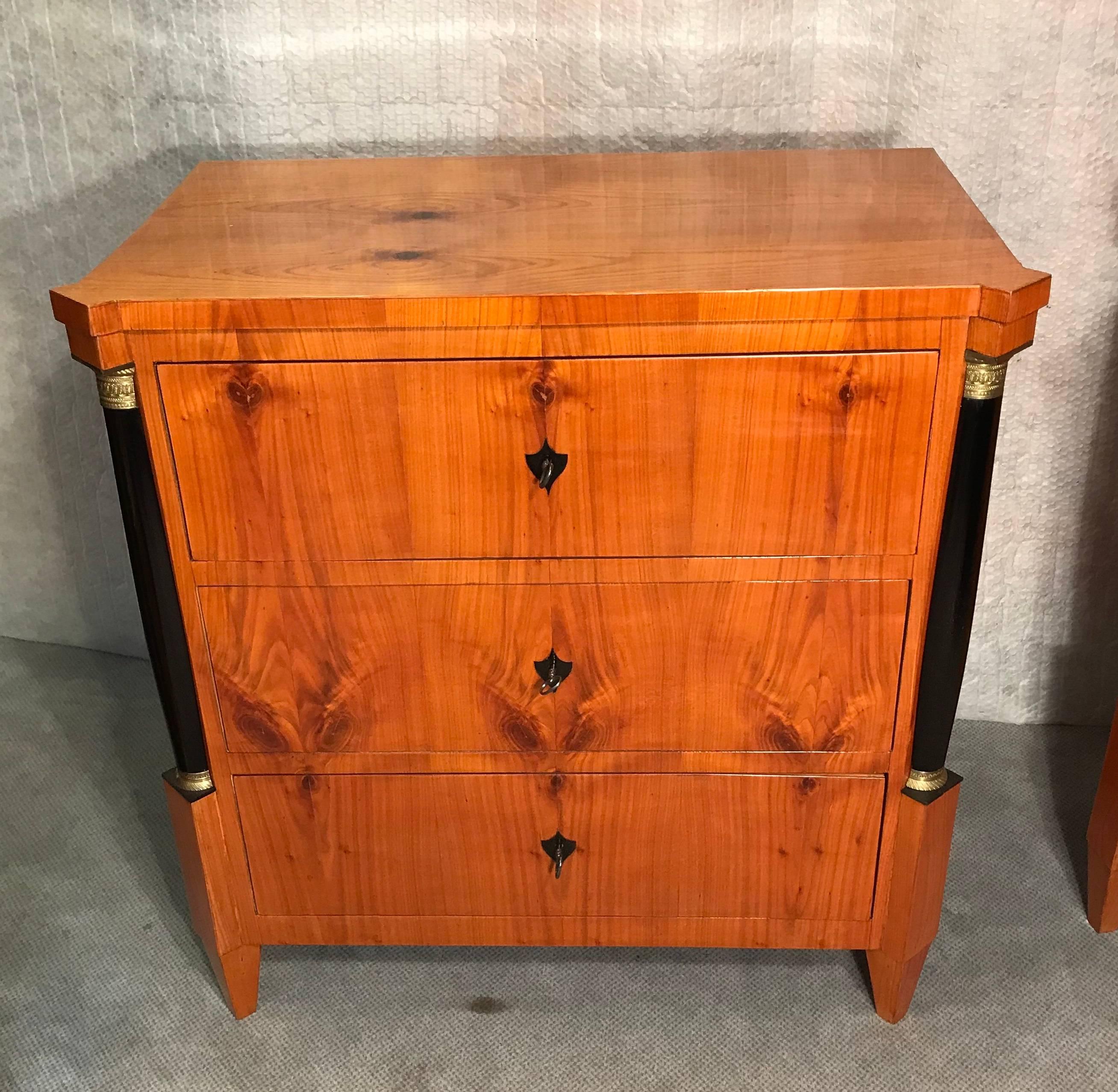 Beautiful pair of Biedermeier commodes, Germany 19th century cherrywood veneer with ebonized columns and brass capitals and bases. In very good condition, refinsihed and French polished. The commodes can also be sold separately. Price per item $6000.