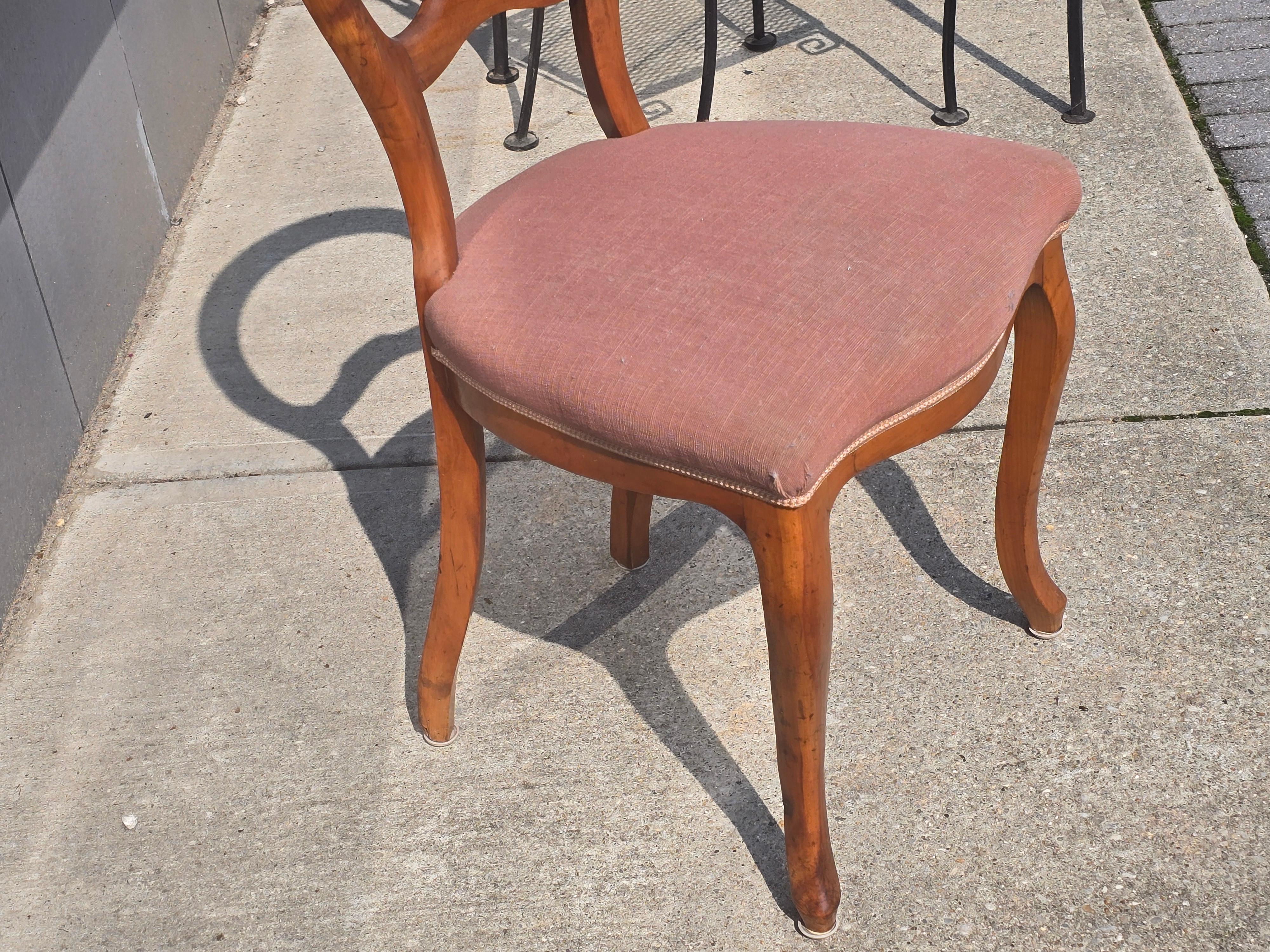 Elegante coppia di poltroncine Biedermeier del 1835-1850 circa, realizzate in legno di frutto con le linee pulite e scultoree che definiscono il successivo periodo Biedermeier. Ciascuna di esse presenta un grazioso schienale a palloncino con un