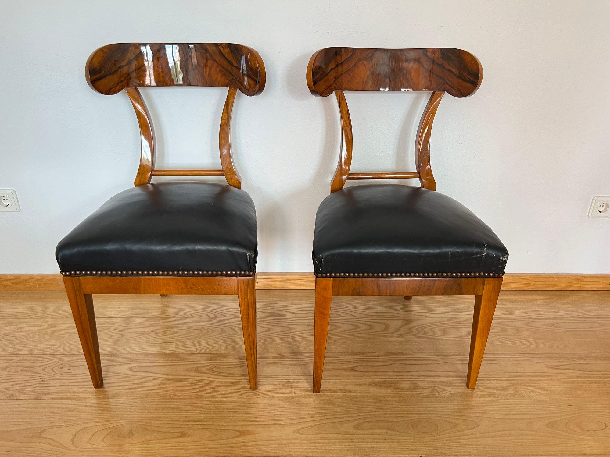 Elegante paire de chaises-pelles Biedermeier en noyer provenant d'Autriche vers 1820.

Plaqué noyer et massif. Le dos de la planche est fortement incurvé.
Pieds carrés fuselés, droits à l'avant, courbés à l'arrière. Barre intermédiaire en baguette
